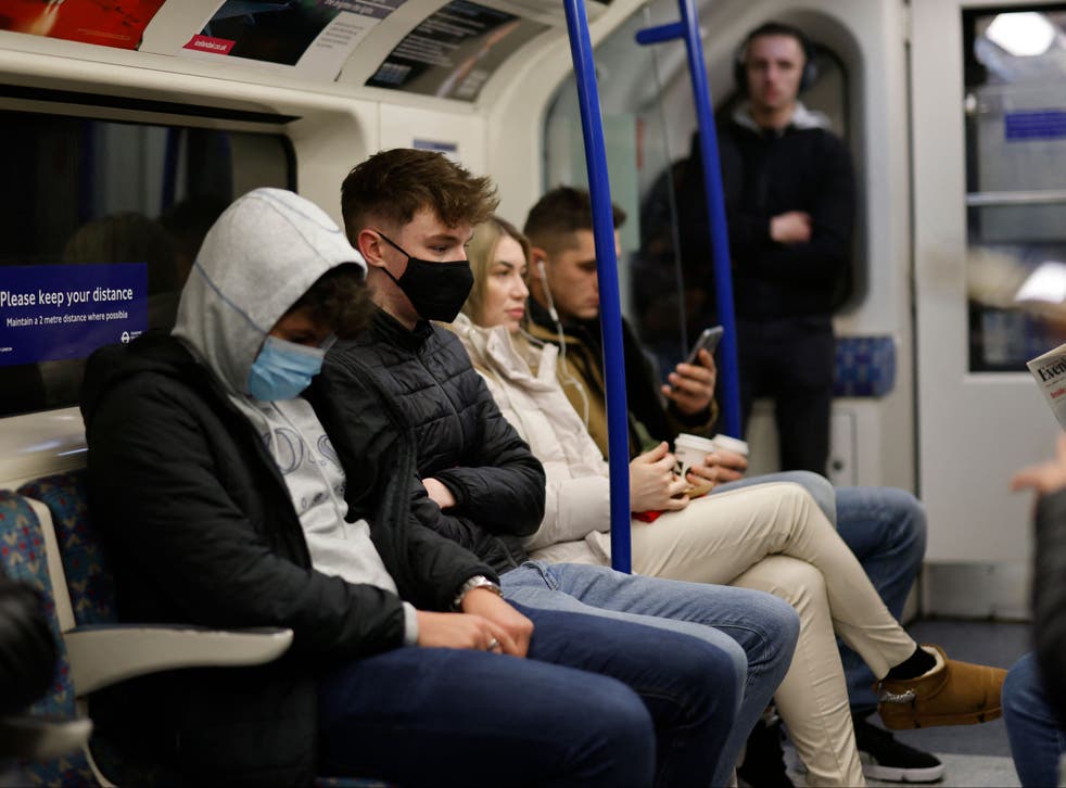 <p>Passengers, some wearing face coverings, travel on the London</p>