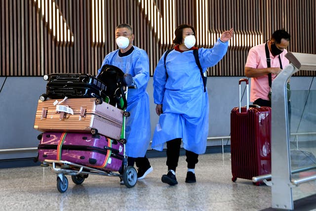 <p>International travellers wearing PPE arrive at Melbourne’s Tullamarine Airport</p>
