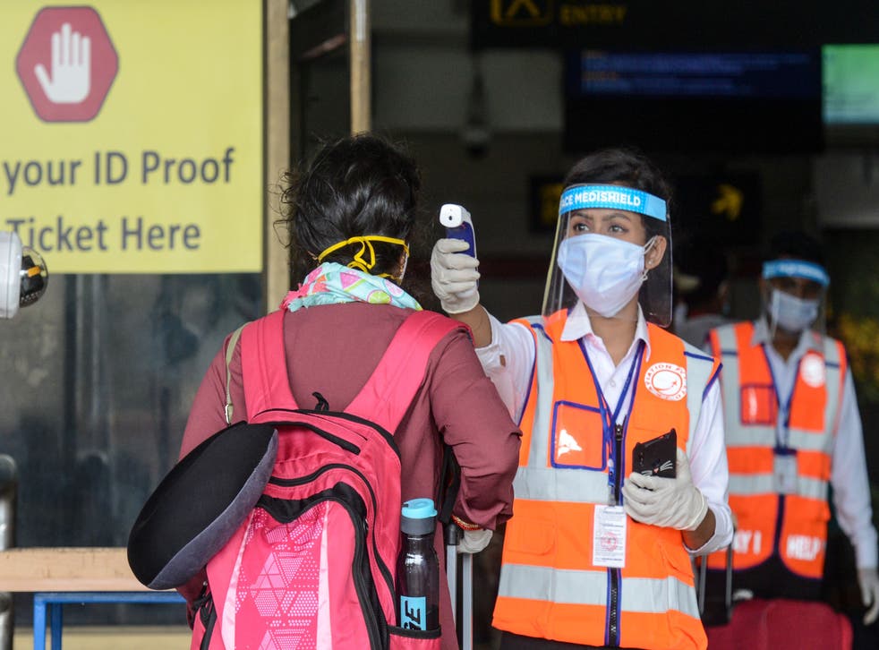 <p>File: An airport employee wearing a face shield checks the body temperature of a passenger in India </p>