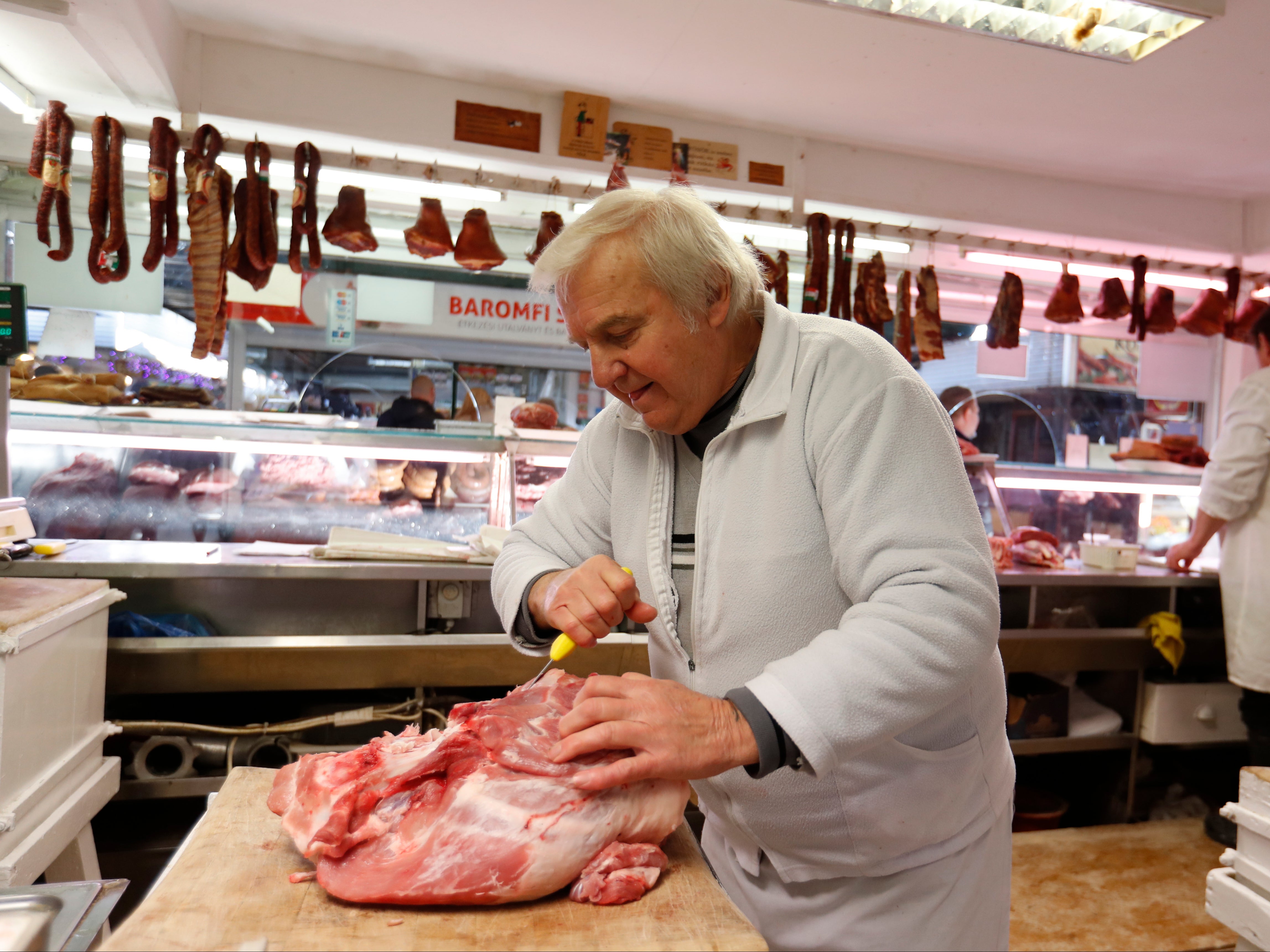 Vendor Misi Kovacs prepers the meat to sell, in a food market in Budapest, Hungary