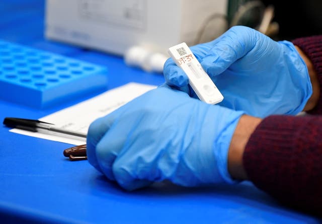 Los trabajadores de la salud y los voluntarios manejan muestras de pruebas de flujo lateral y registran los resultados mientras los estudiantes toman las pruebas de la enfermedad por coronavirus en Harris Academy Beckenham