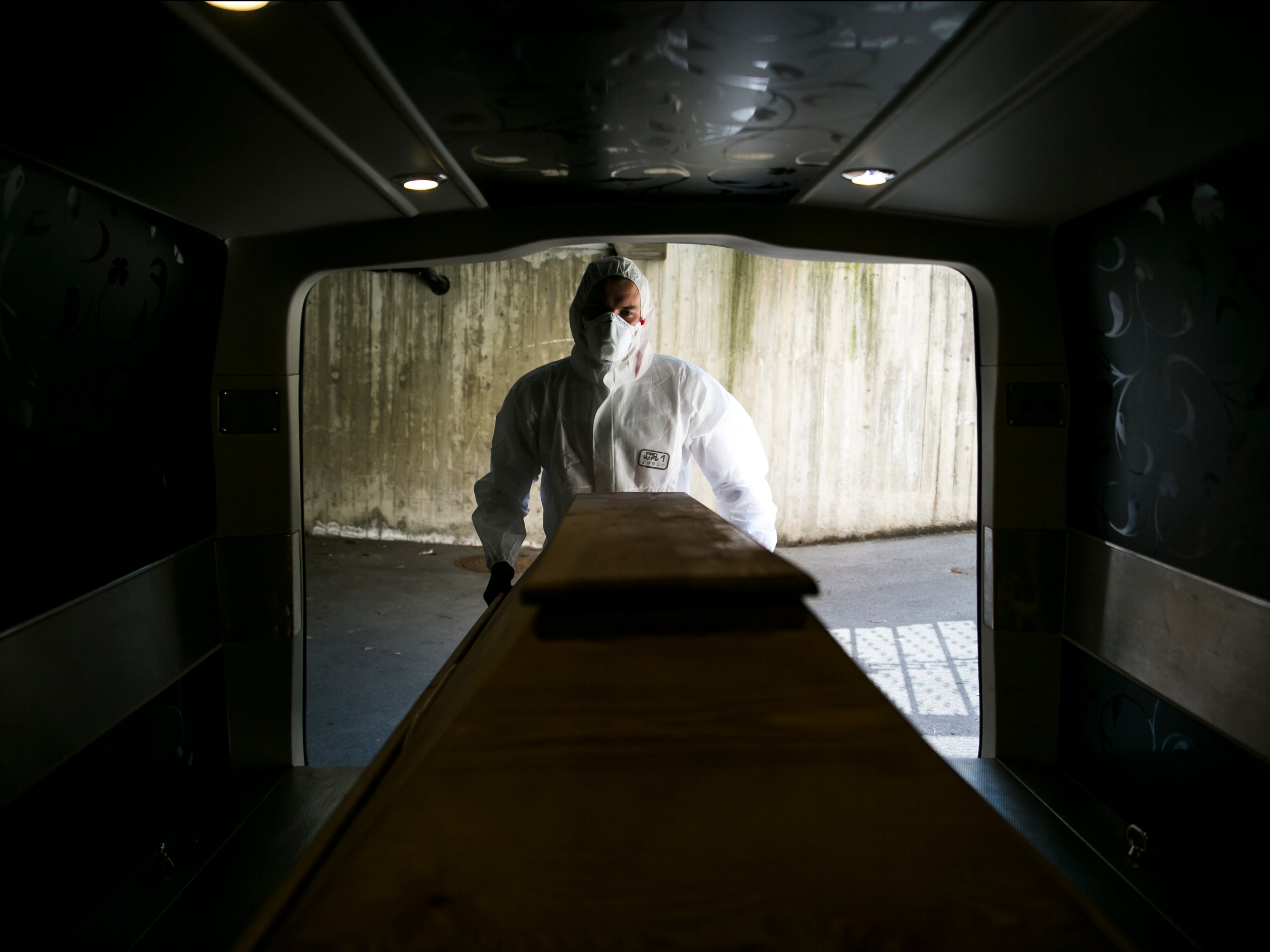File image: An undertaker worker pushes a coffin carrying a deceased Covid-19 victim into a mortuary van at a morgue in Austria