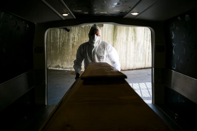 <p>File image: An undertaker worker pushes a coffin carrying a deceased Covid-19 victim into a mortuary van at a morgue in Austria</p>