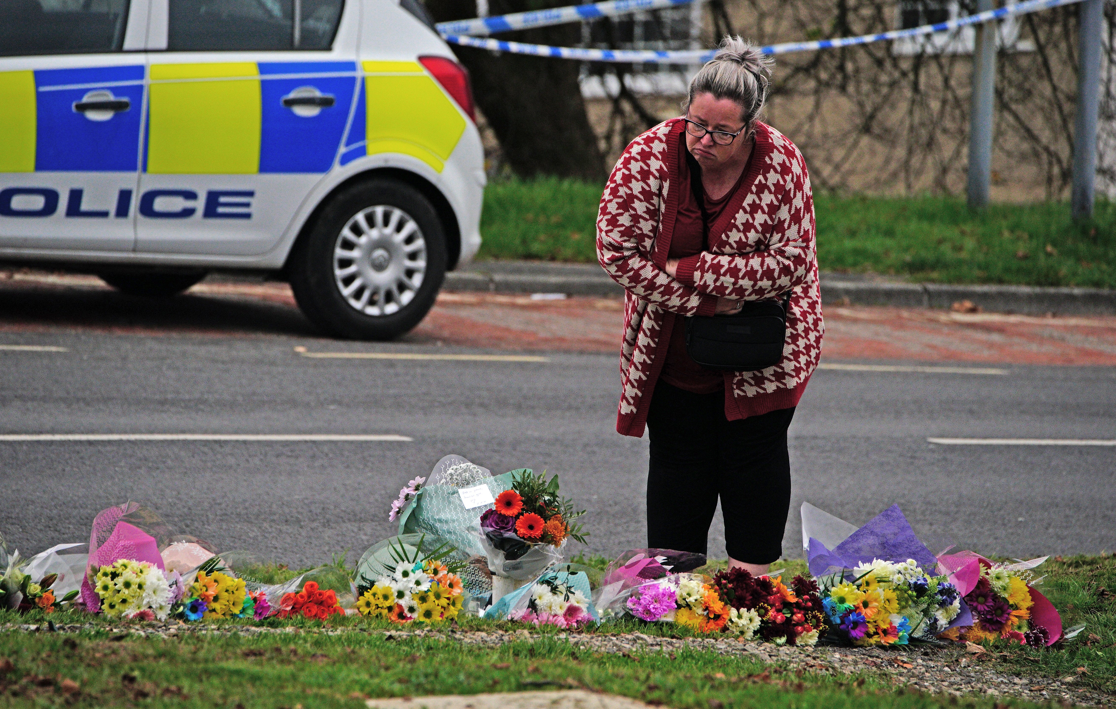 A woman lays flowers on Sheepstor Road in Plymouth (Ben Birchall/PA)
