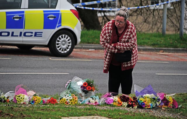<p>A woman lays flowers on Sheepstor Road in Plymouth (Ben Birchall/PA)</p>
