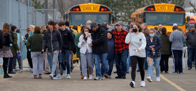 <p>Parents walk away with their kids from the Meijer’s parking lot, where many students gathered following an active shooter situation at Oxford High School, Michigan </p>