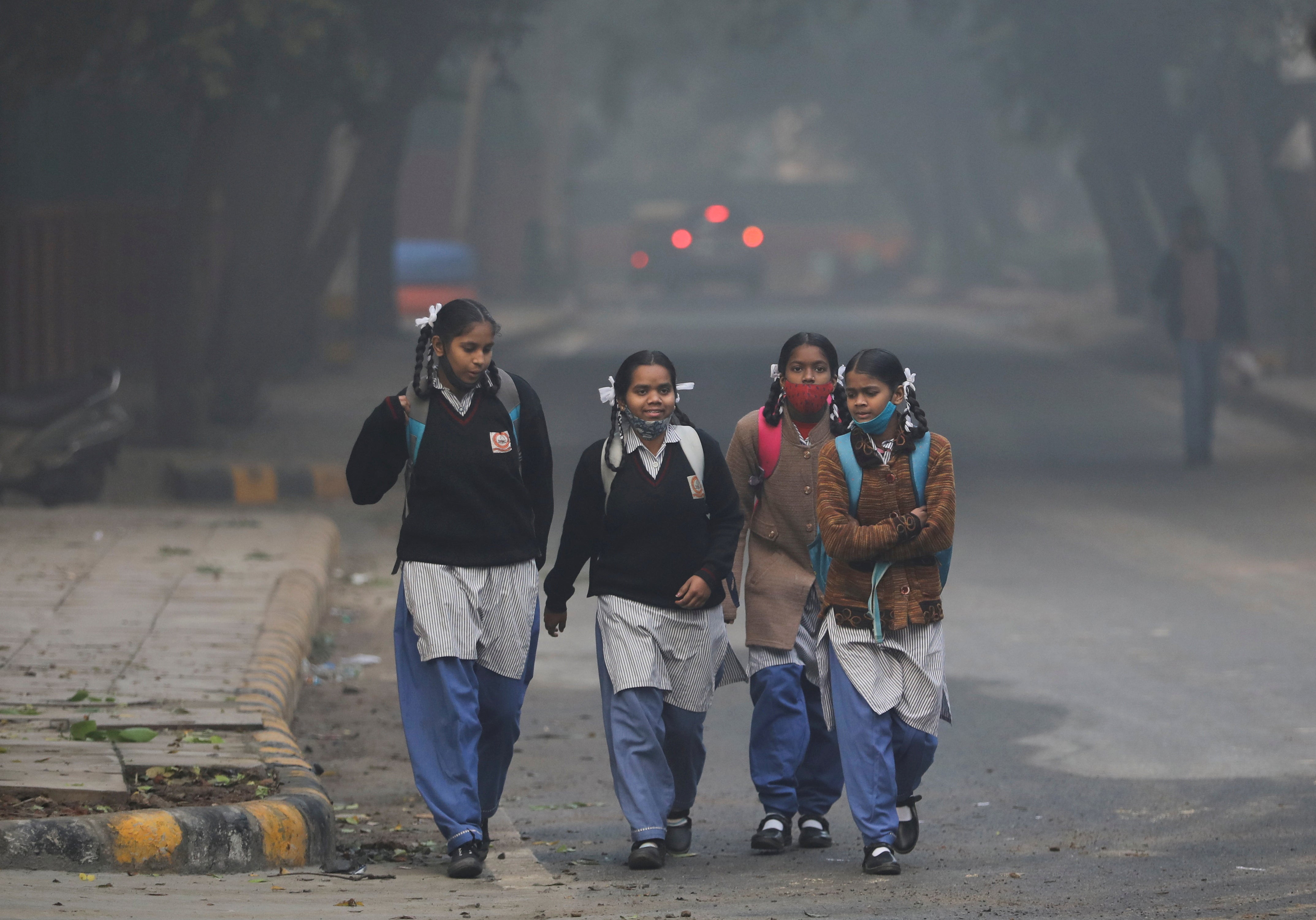 Schoolgirls walk towards a school as they reopened after remaining closed for nearly 15 days due to a spike in air pollution, on a smoggy morning in New Delhi