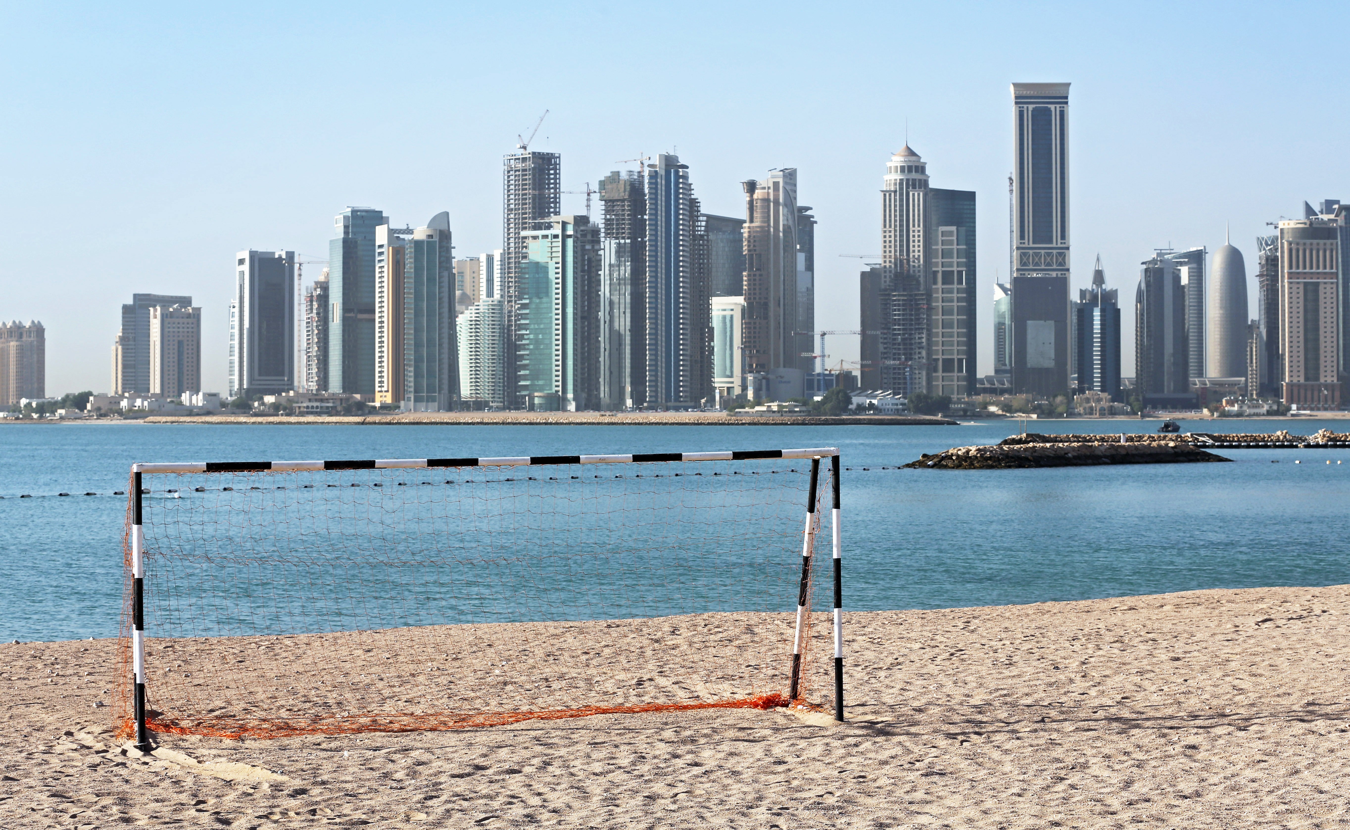 A football goal at a beach in front of the skyline of Doha, Qatar