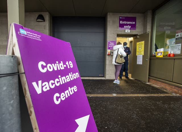 A member of the Belfast Health and Social Care Trust greets a person as they arrive at the Covid-19 vaccination centre at Belfast’s Royal Victoria Hospital (Liam McBurney/PA)