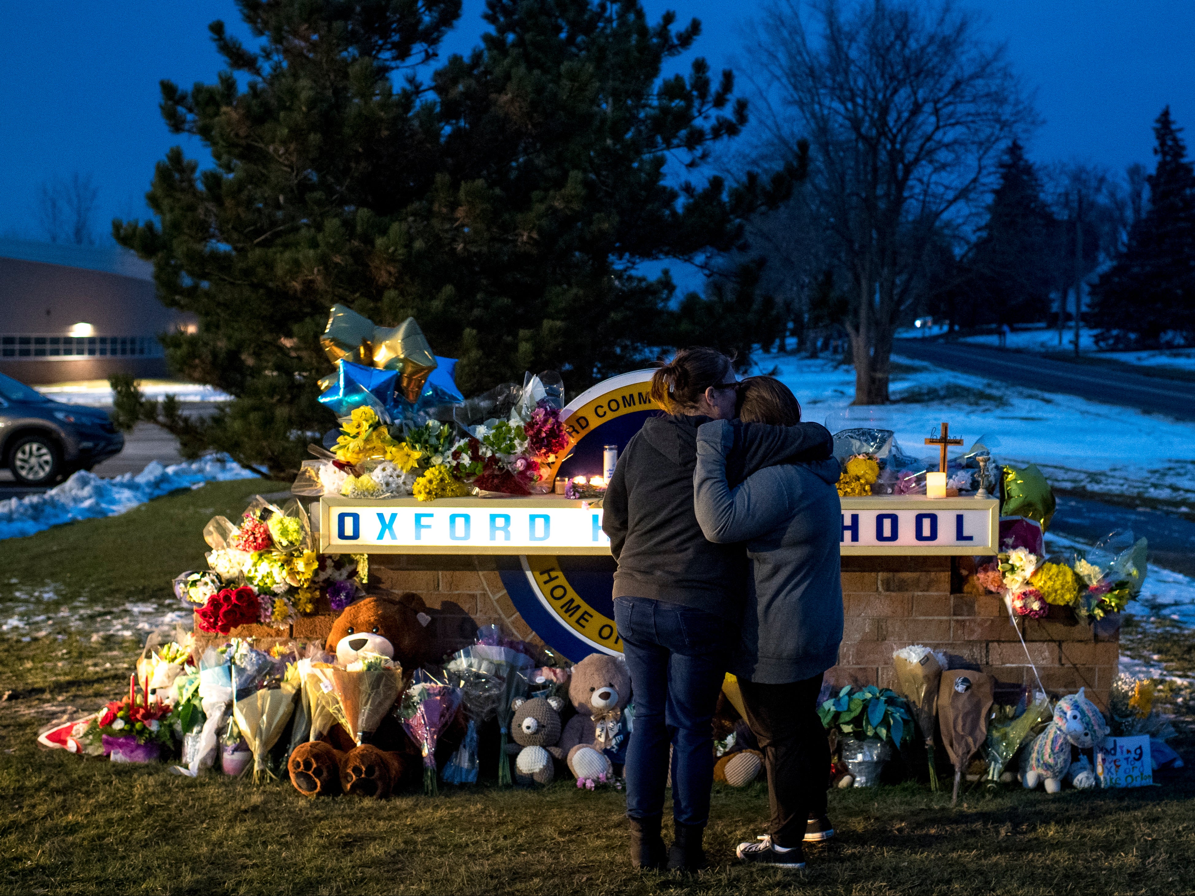 People mourn at a growing memorial outside Oxford High School