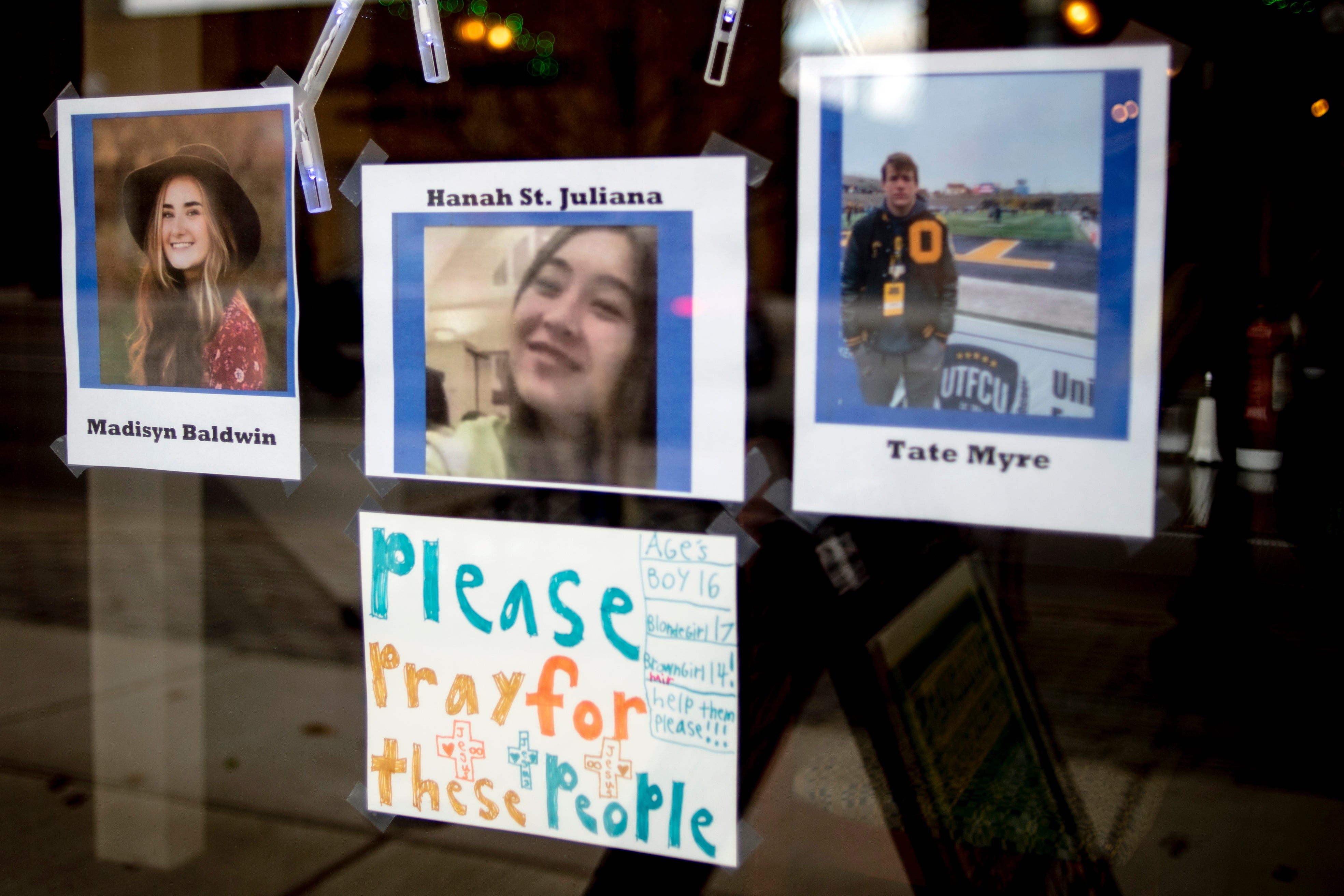 Photos of three of the four teens killed in the Oxford High School shooting are posted on the window at Sullivan’s Public House Restaurant and Bar on Thursday