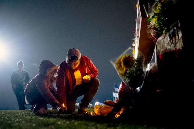 <p>Waterford resident Andrew Baldwin, cousin of Madisyn Baldwin, places candles at the base of a a memorial with his 5-year-old daughter Ariyah Baldwin</p>