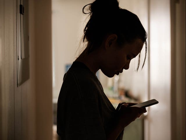 <p>A girl looks at her phone</p>