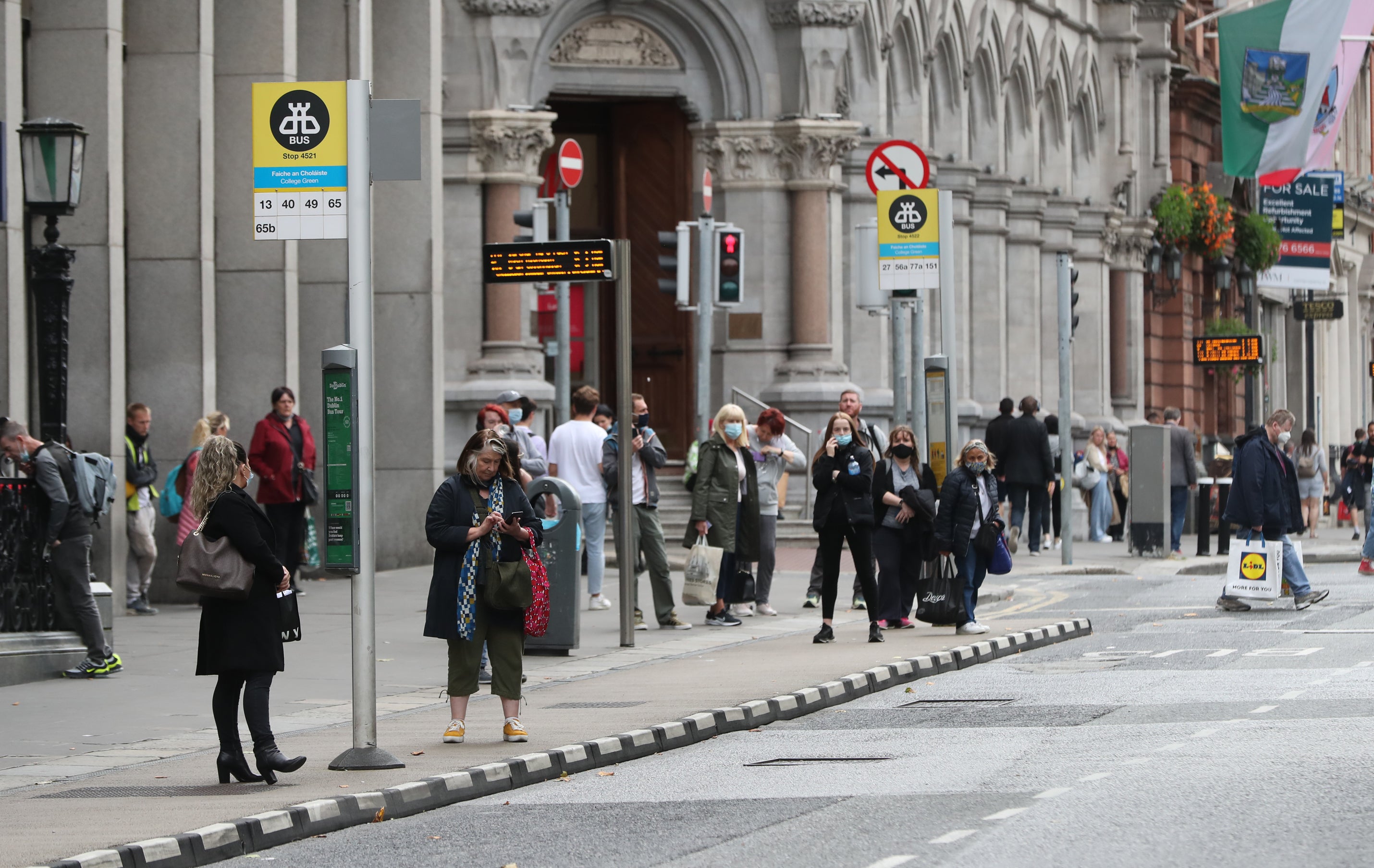 Passengers wait for a bus in Dublin city centre (PA)