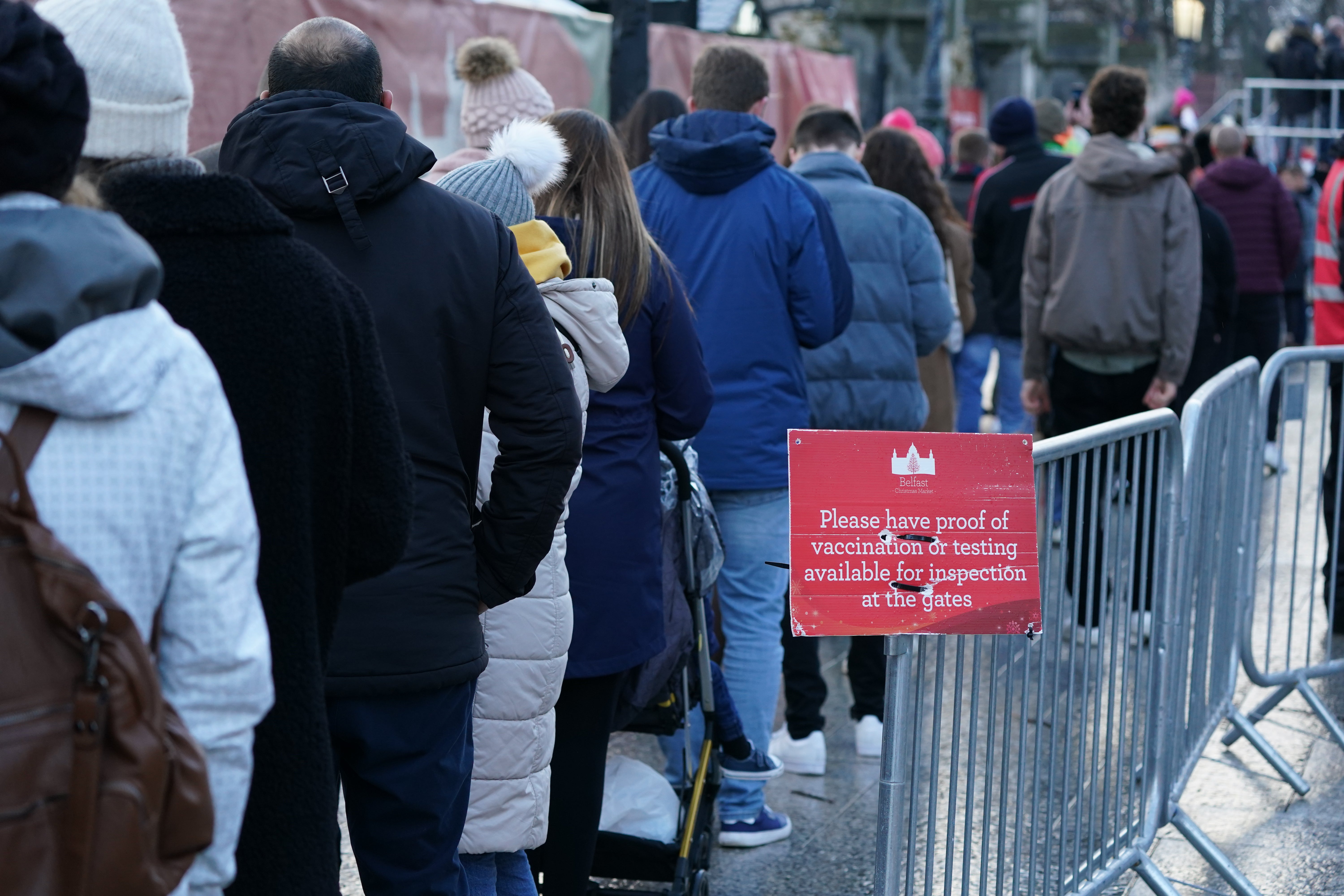 People queue to show their Covid certs to enter the Christmas market outside Belfast City Hall (Brian Lawless/PA)