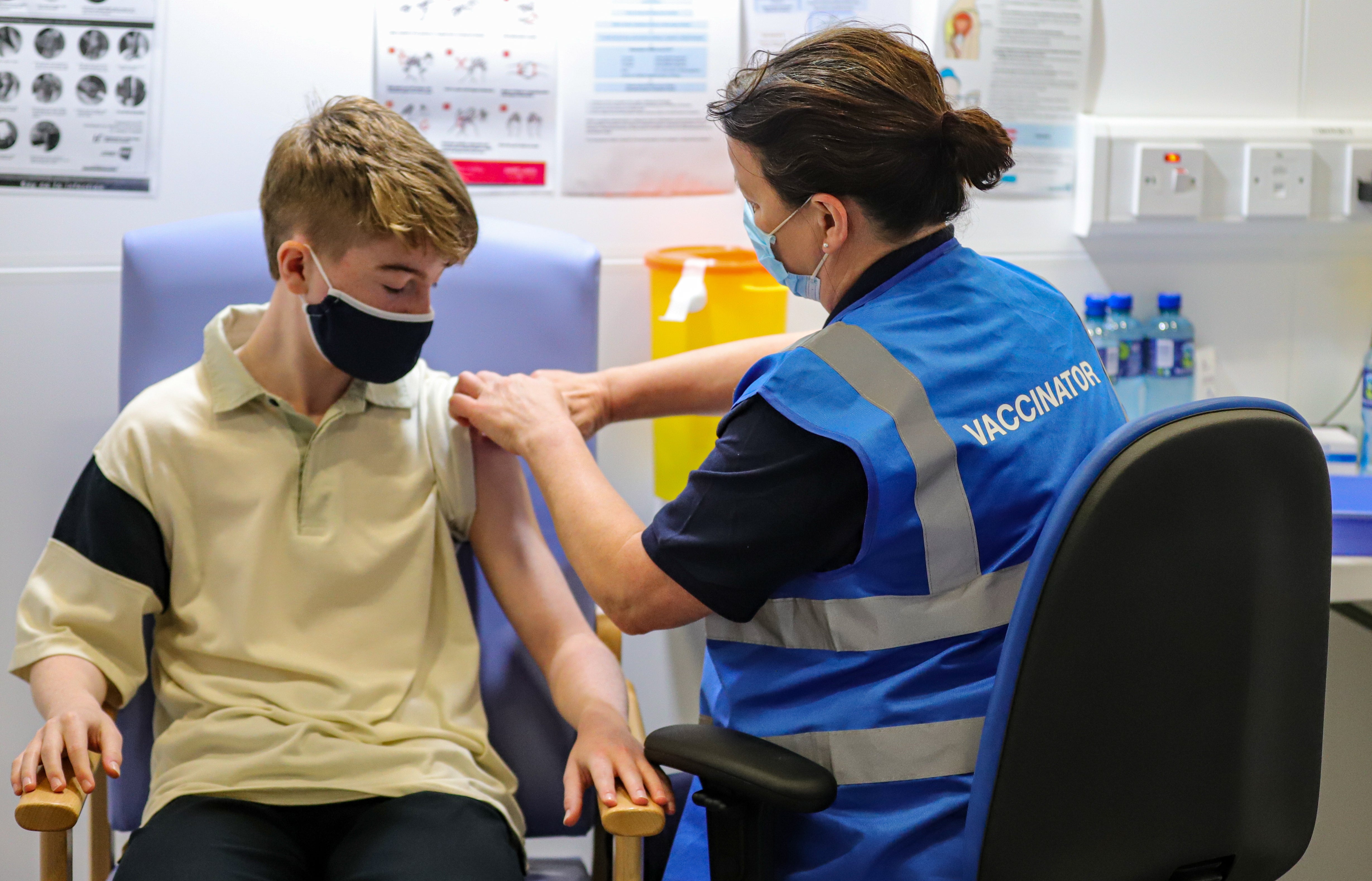 Kevin Mckeon, 14, receives his first dose of the Covid-19 vaccine from vaccinator Geraldine Flynn at the Citywest vaccination centre in Dublin (Damien Storan/PA)