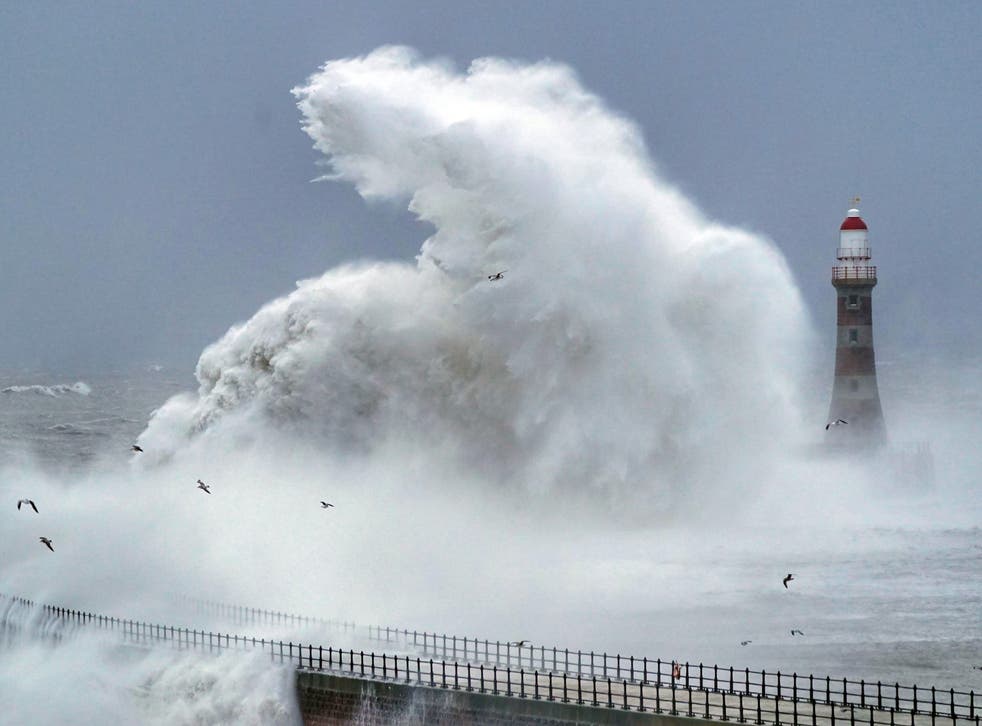 Huge waves crash against the sea wall and Roker Lighthouse in Sunderland in the tail end of Storm Arwen (Owen Humphreys/PA)