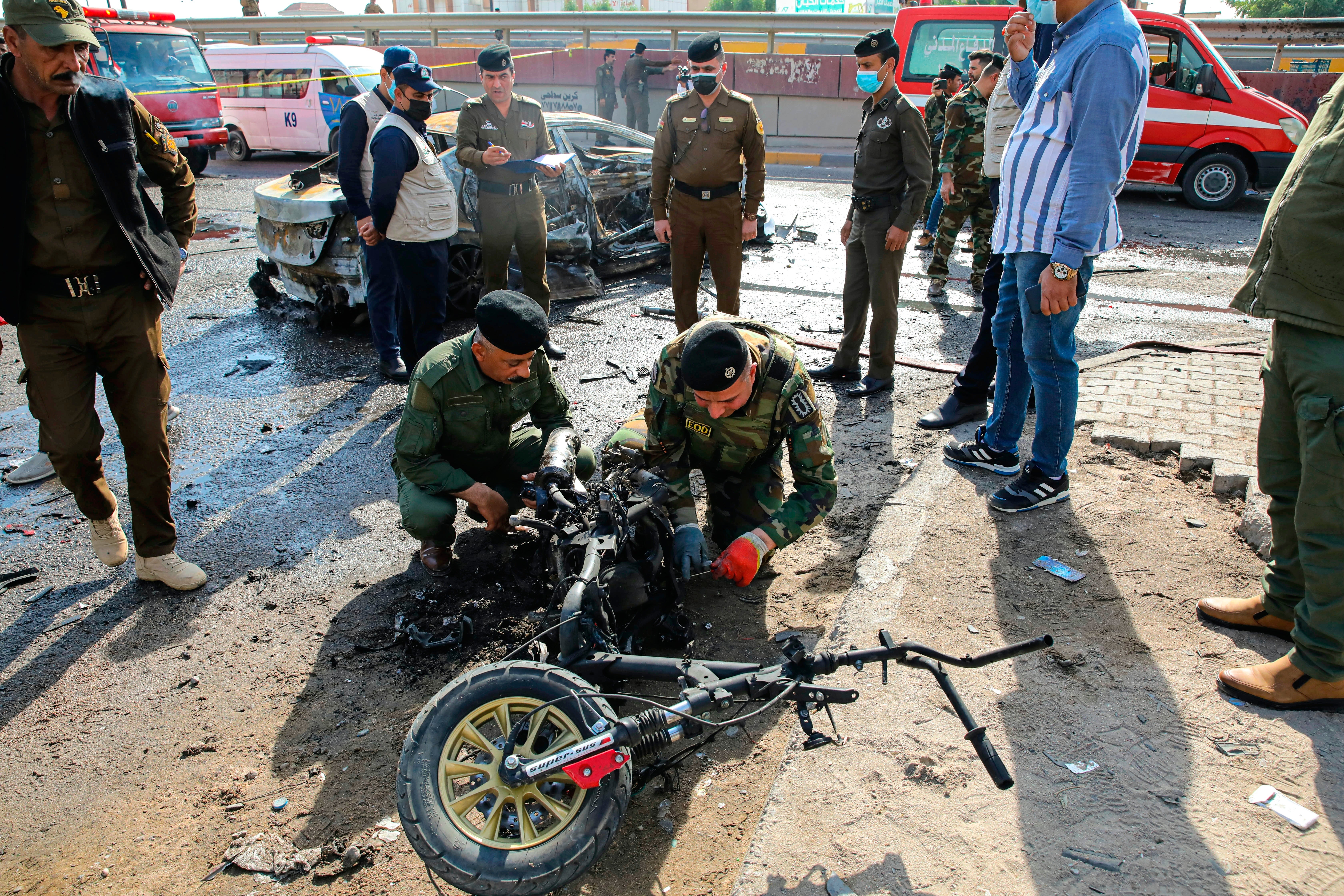 Security forces inspect a motorcycle at the site of an explosion in Basra, Iraq