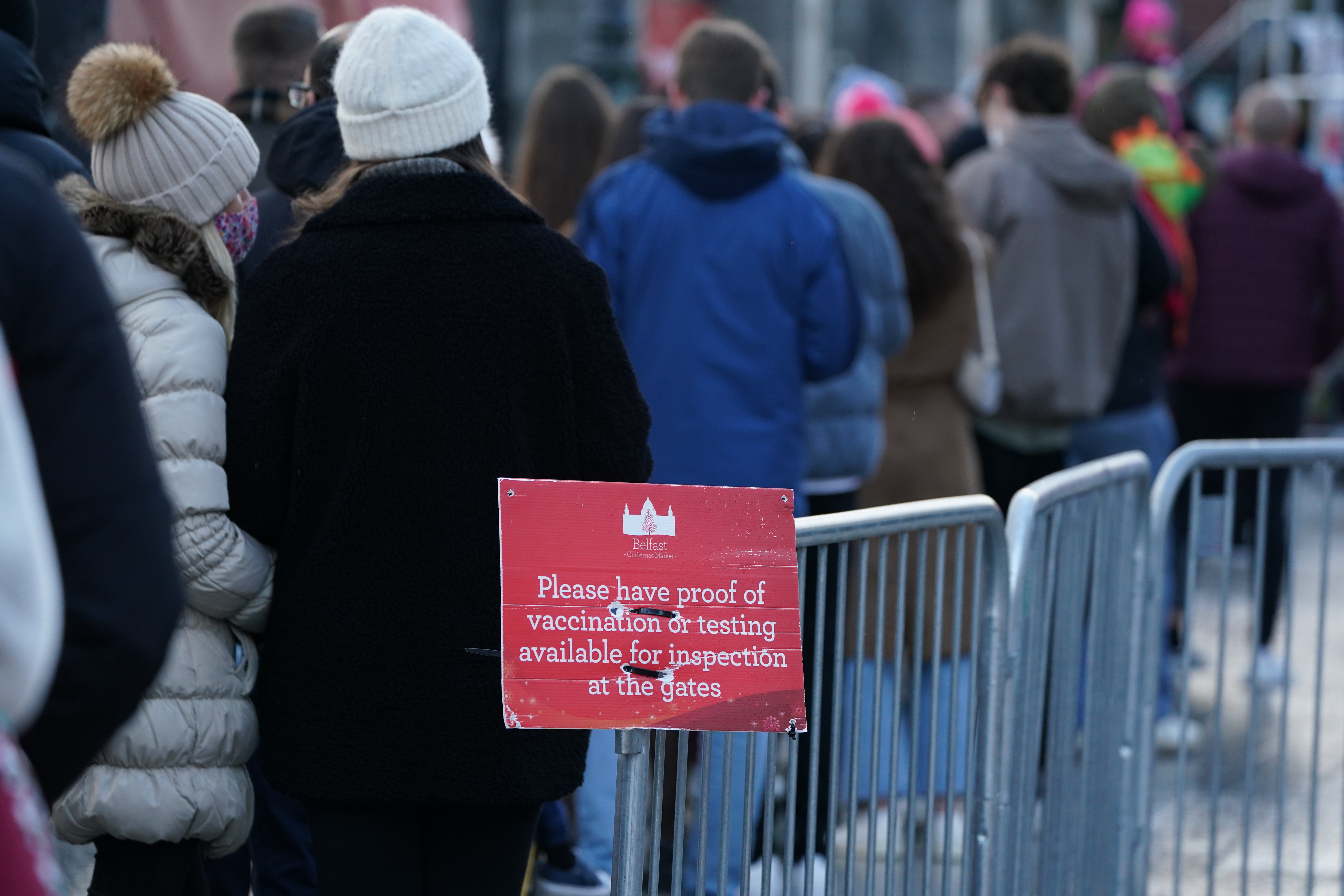 People queue to show Covid certificates to enter the Christmas market outside Belfast City Hall (Brian Lawless/PA)