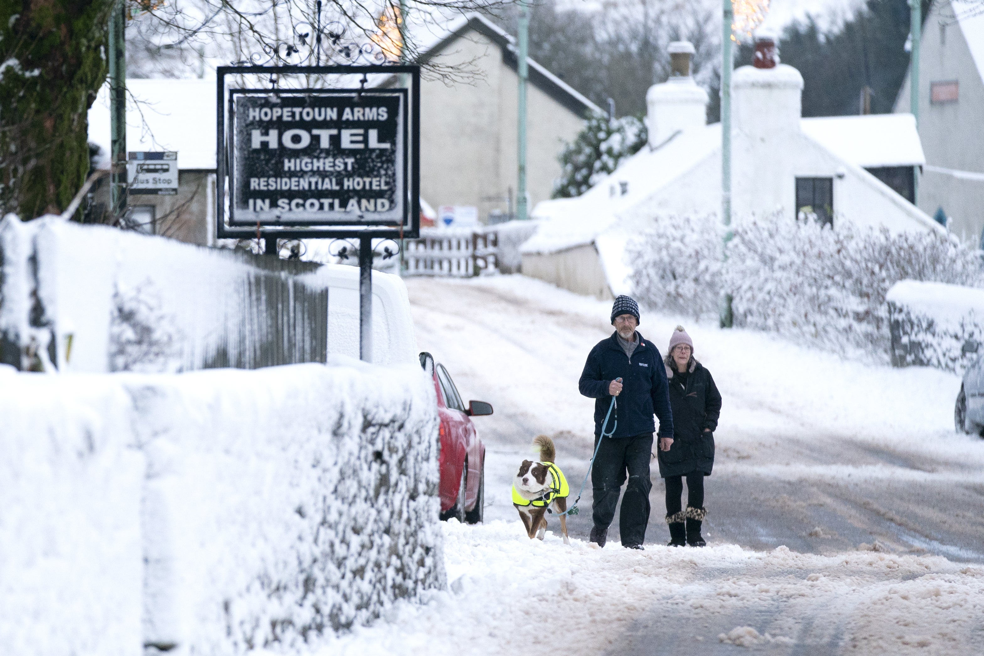 A couple walk their dog through the snow in Leadhills, South Lanarkshire, as Storm Barra hit the UK (Jane Barlow/PA)
