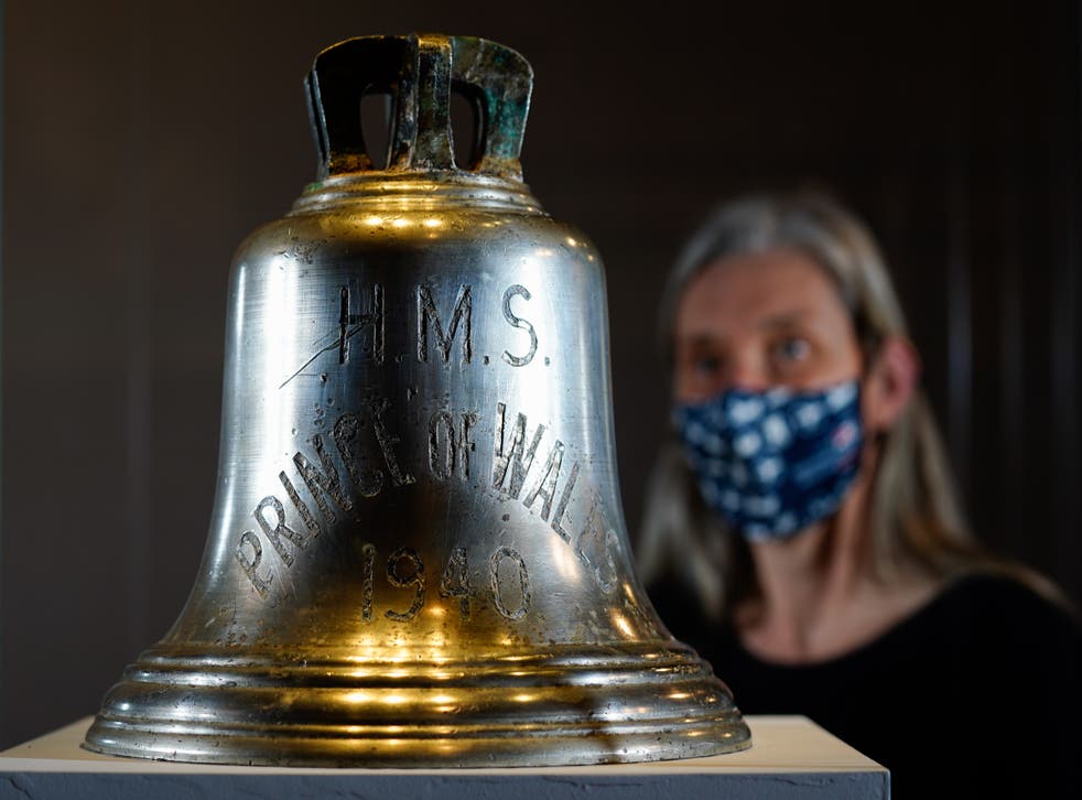 Victoria Ingles, senior curator at the National Museum of the Royal Navy, looks at the ship’s bell from HMS Prince of Wales which was sunk in the Second World War (Andrew Matthews/PA)