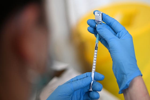 <p>A clinician prepares a dose of the Pfizer vaccine at a vaccination centre in west London</p>