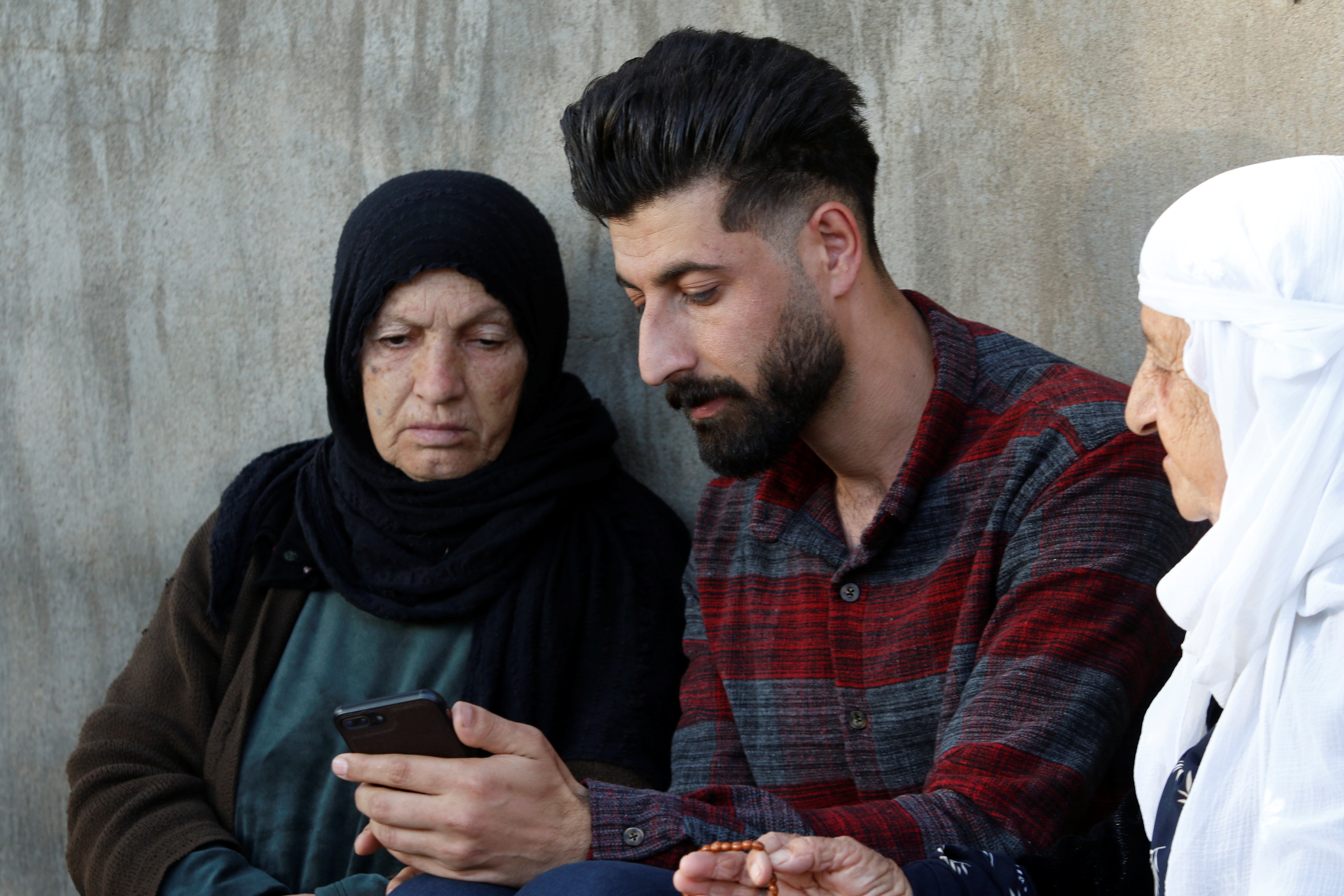 Hemn Amin, an Iraqi Kurd who was evacuated from Belarus, sits with his relatives in city of Khurmal, Iraq, November 30, 2021