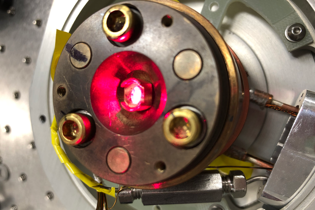 <p>A strong laser is seen illuminating a material in a low-temperature chamber. The laser is being used to change the material's degree of transparency</p>