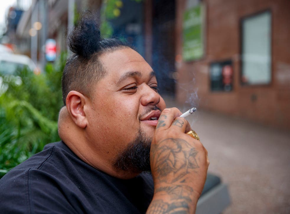 <p>A man smoking on a street in Auckland</p>