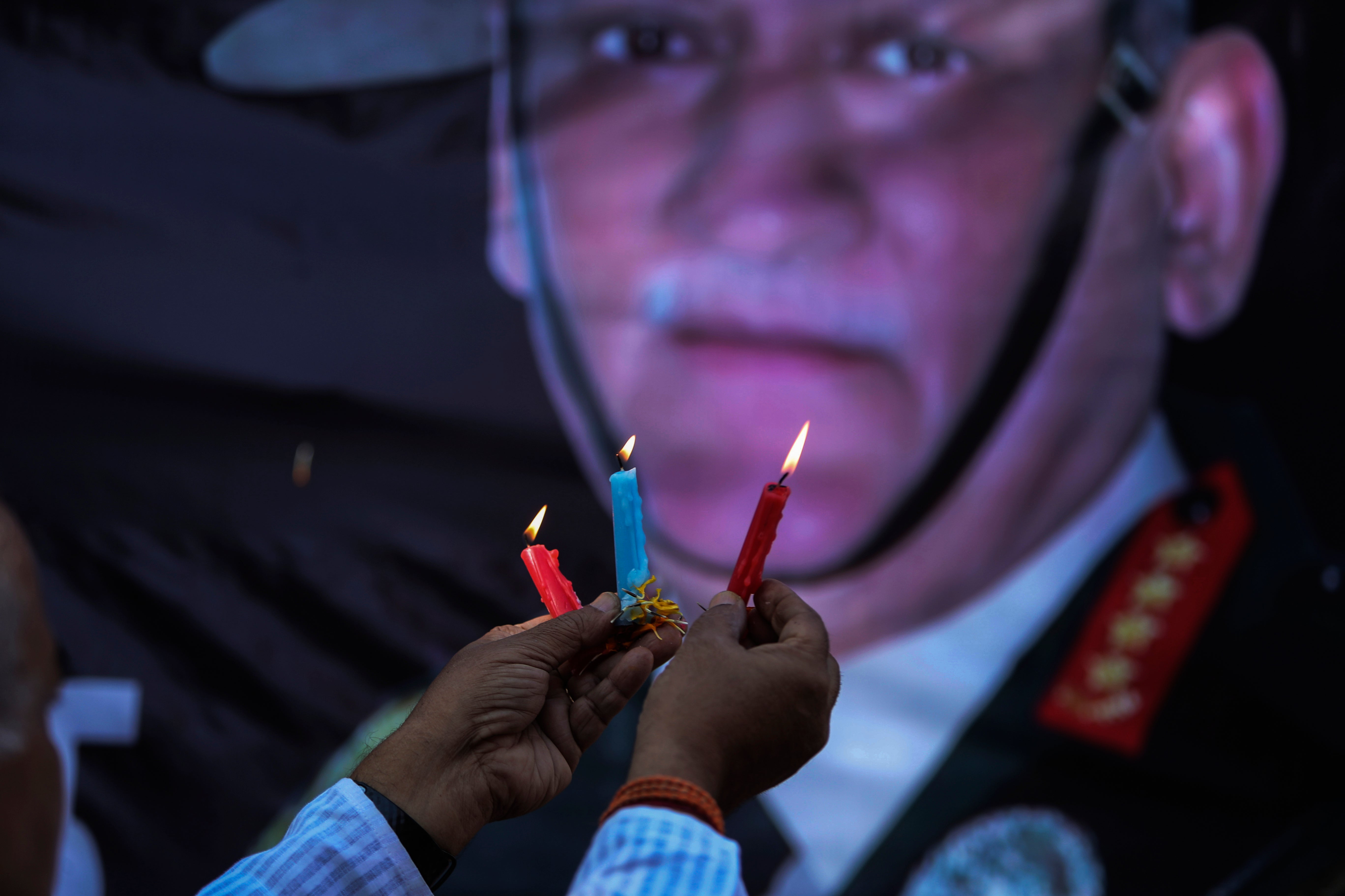 A man lights candles before a portrait of India’s military chief, Gen. Bipin Rawat, who was killed in a helicopter crash on Wednesday