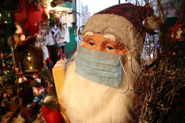 A Santa with a face covering on at a Christmas Shop in Stirling (Andrew Milligan/PA)