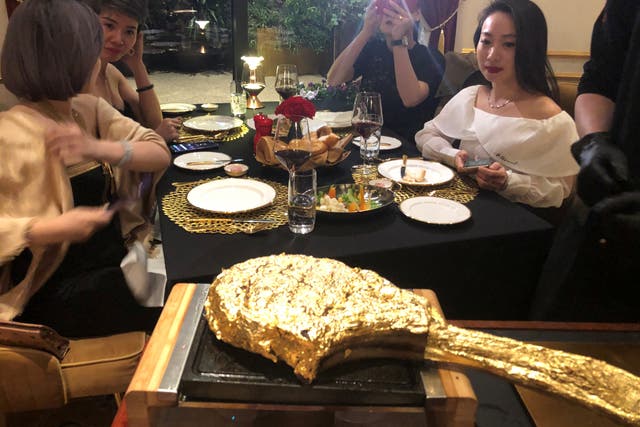 <p>A customer takes pictures of a gold leaf-coated steak at the Dolce By Wyndham Hanoi Golden Lake hotel in Hanoi</p>