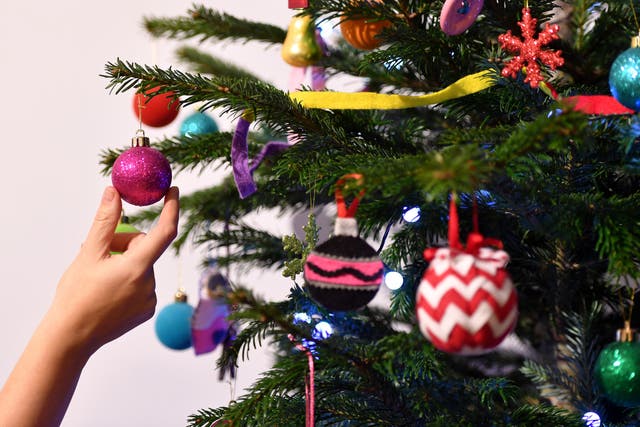 A woman adjusts a decoration on a Christmas tree.