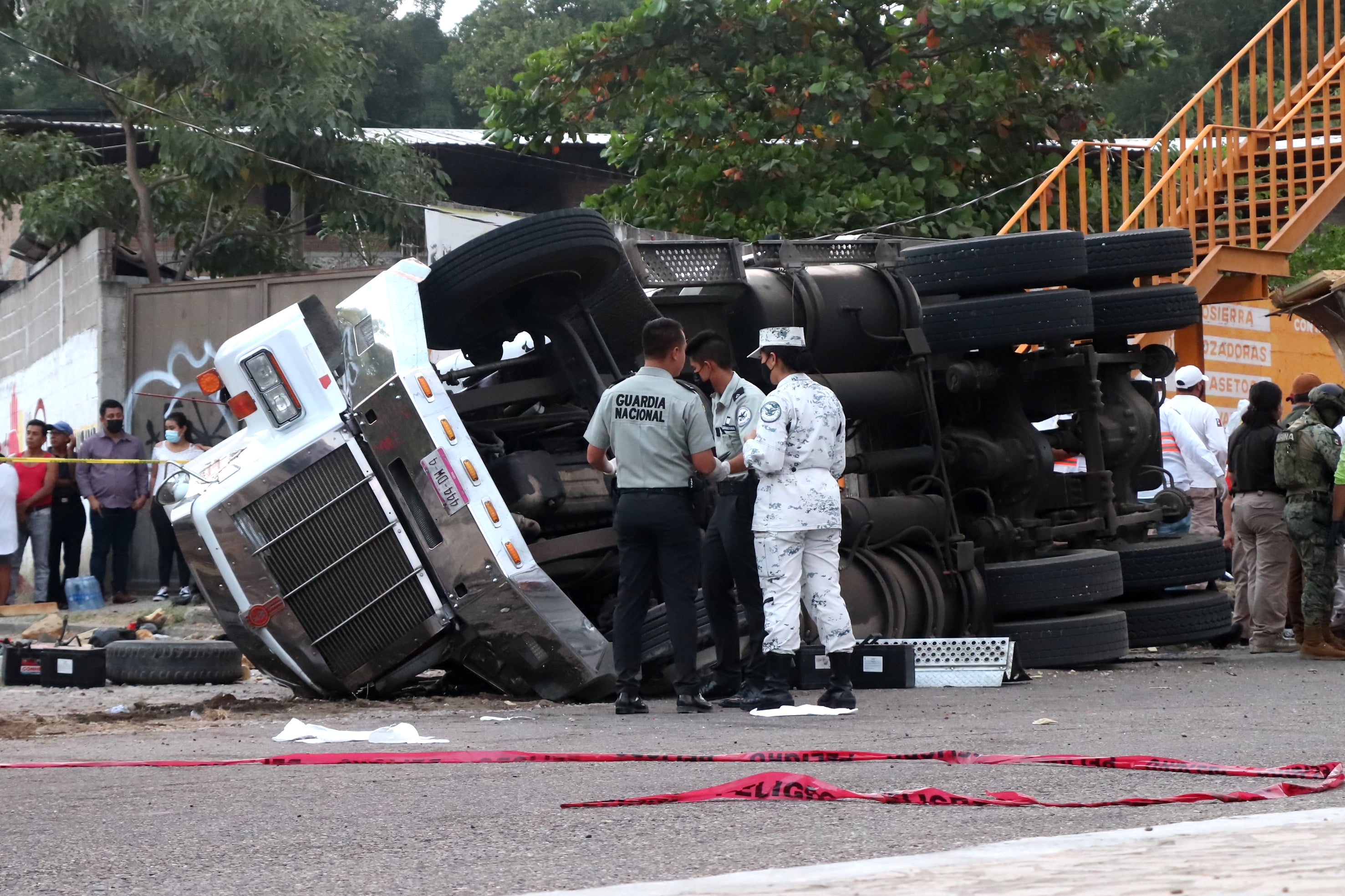 <p>Officers next to where the truck rolled over killing dozens of migrants in Tuxtla Gutierrez, Mexico</p>