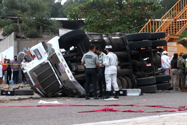 <p>Officers next to where the truck rolled over killing dozens of migrants in Tuxtla Gutierrez, Mexico</p>