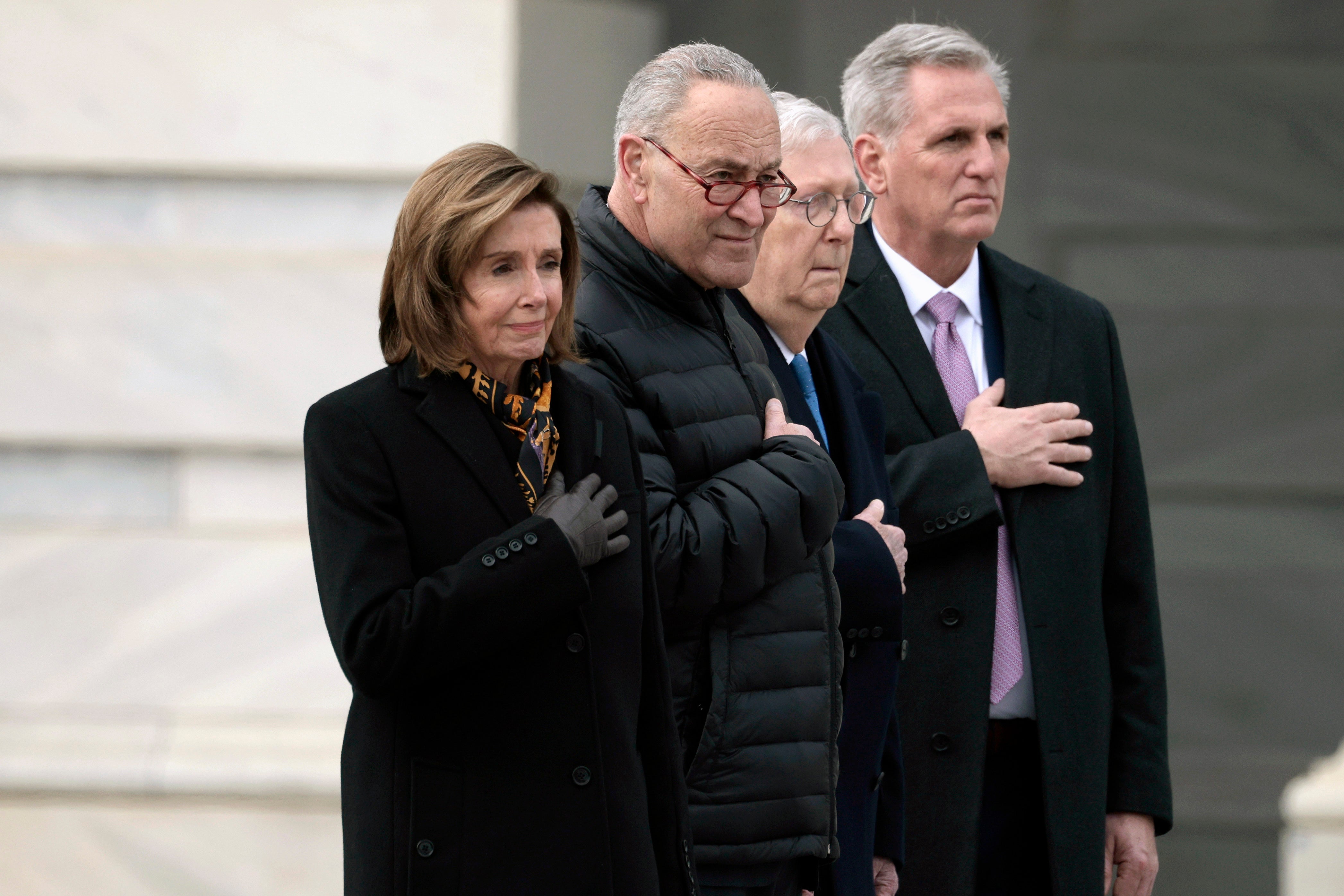 From left, House Speaker Nancy Pelosi of Calif., Senate Majority Leader Chuck Schumer of N.Y., Senate Minority Leader Mitch McConnell of Ky., and House Minority Leader Kevin McCarthy of Calif., watch as the casket of former Sen. Bob Dole, R-Kan., is carried down the East steps of Capitol Hill in Washington, Friday, Dec. 10, 2021, where Dole was lying in state.