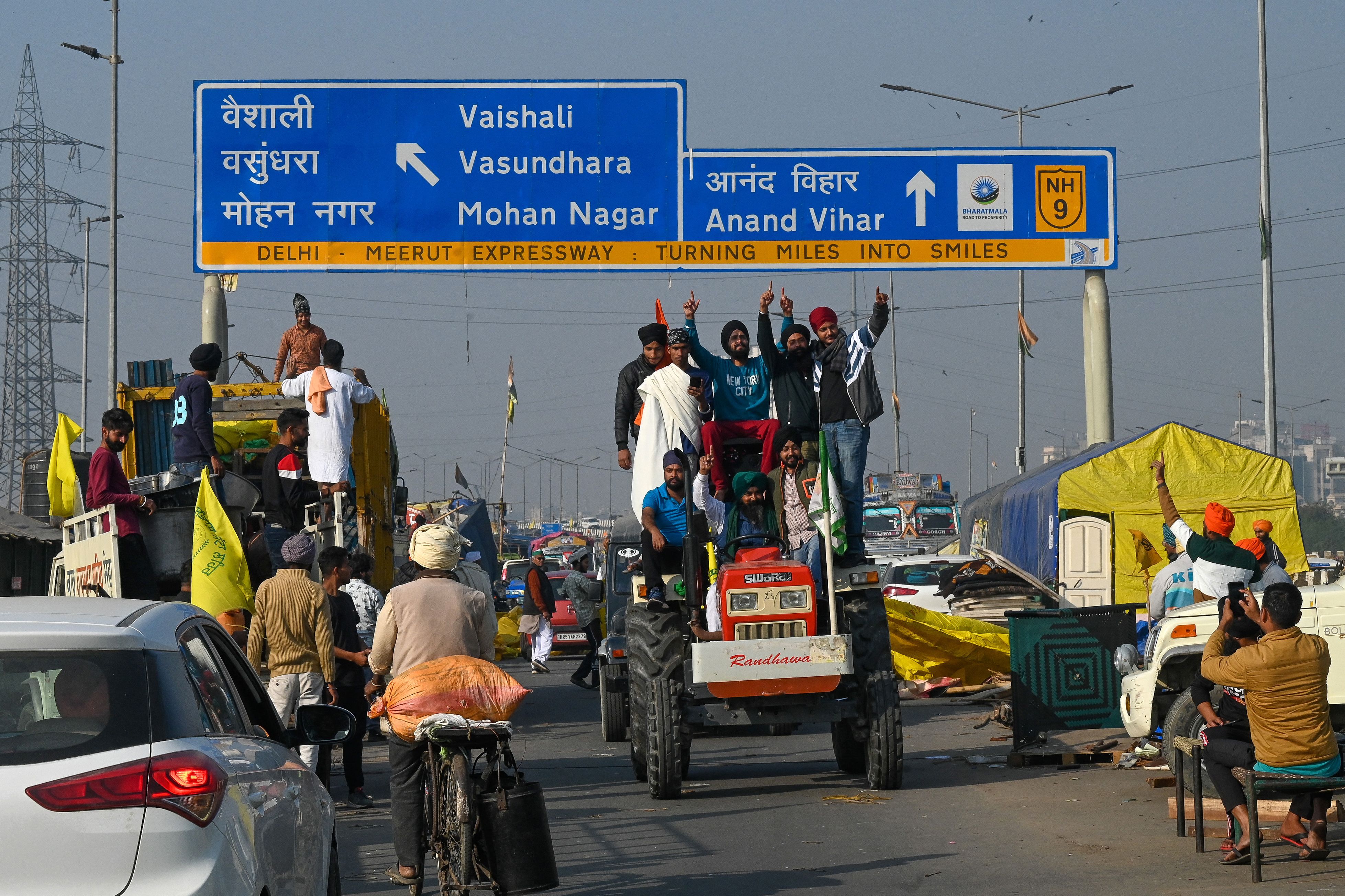 Farmers ride on a tractor as they leave the protest site at the Delhi-Uttar Pradesh state border in Ghazipur on 11 December 2021