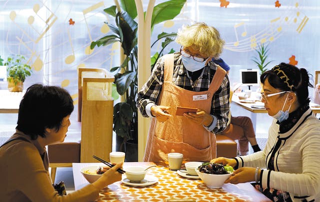<p>Zhu Caiping, 73, serves customers at Forget Me Not Café in Shanghai in October</p>