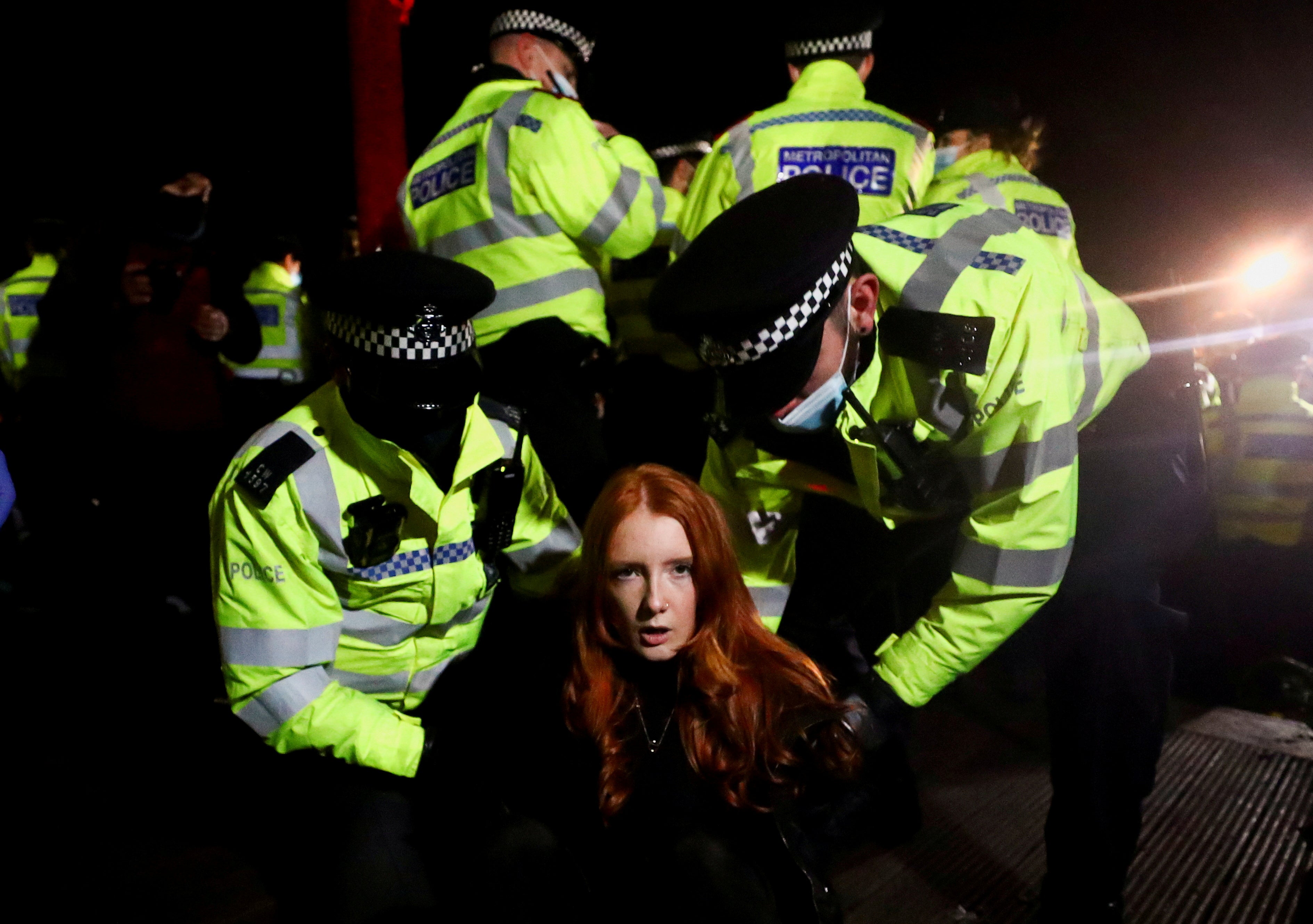 Police detain a woman as people gather at a memorial site in Clapham Common following the murder of Sarah Everard in London