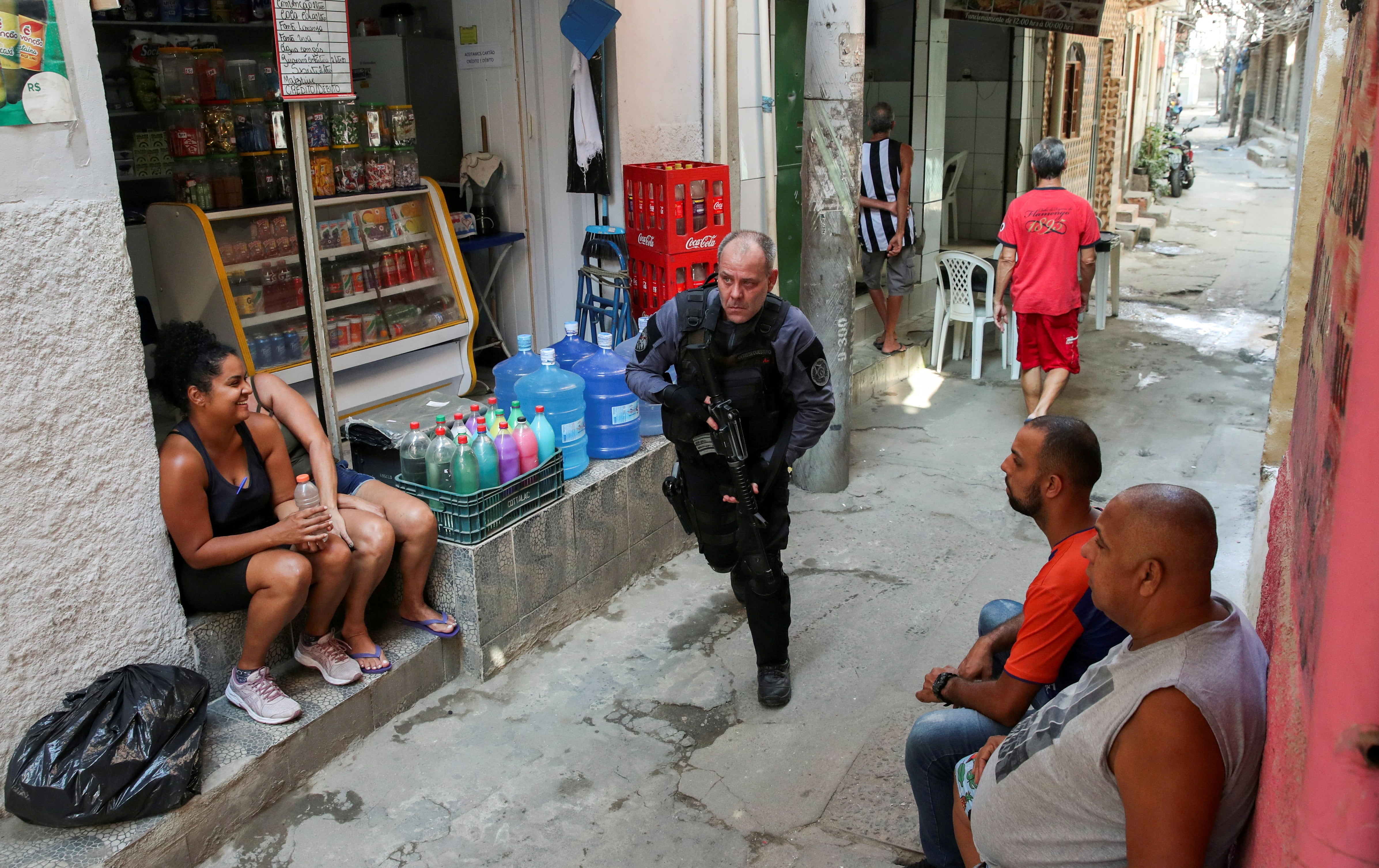 A police officer takes position during an operation against drug dealers in Jacarezinho, Rio de Janeiro
