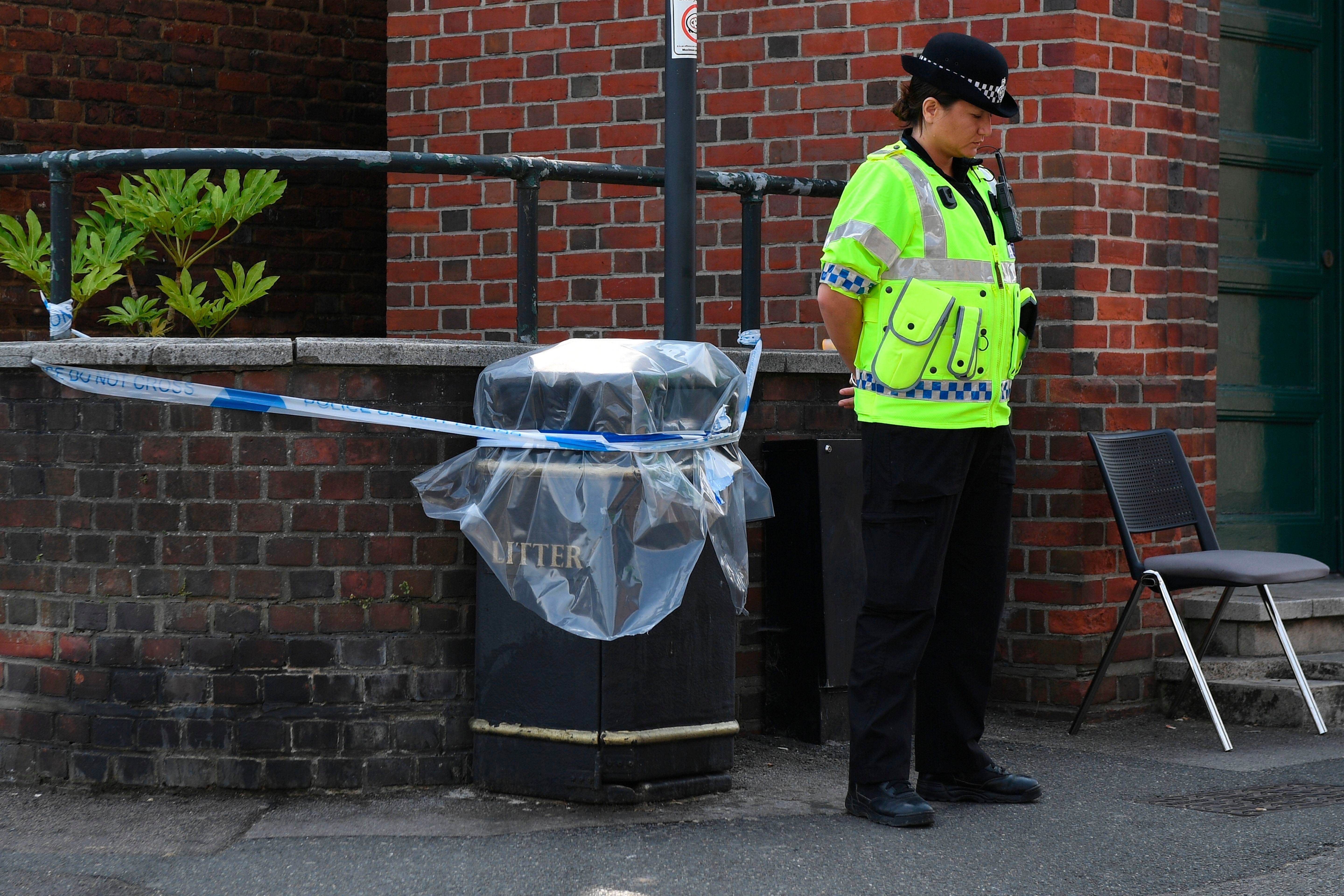 A police officer stands guard over a public rubbish bin that is cordoned off in Amesbury, near Salisbury