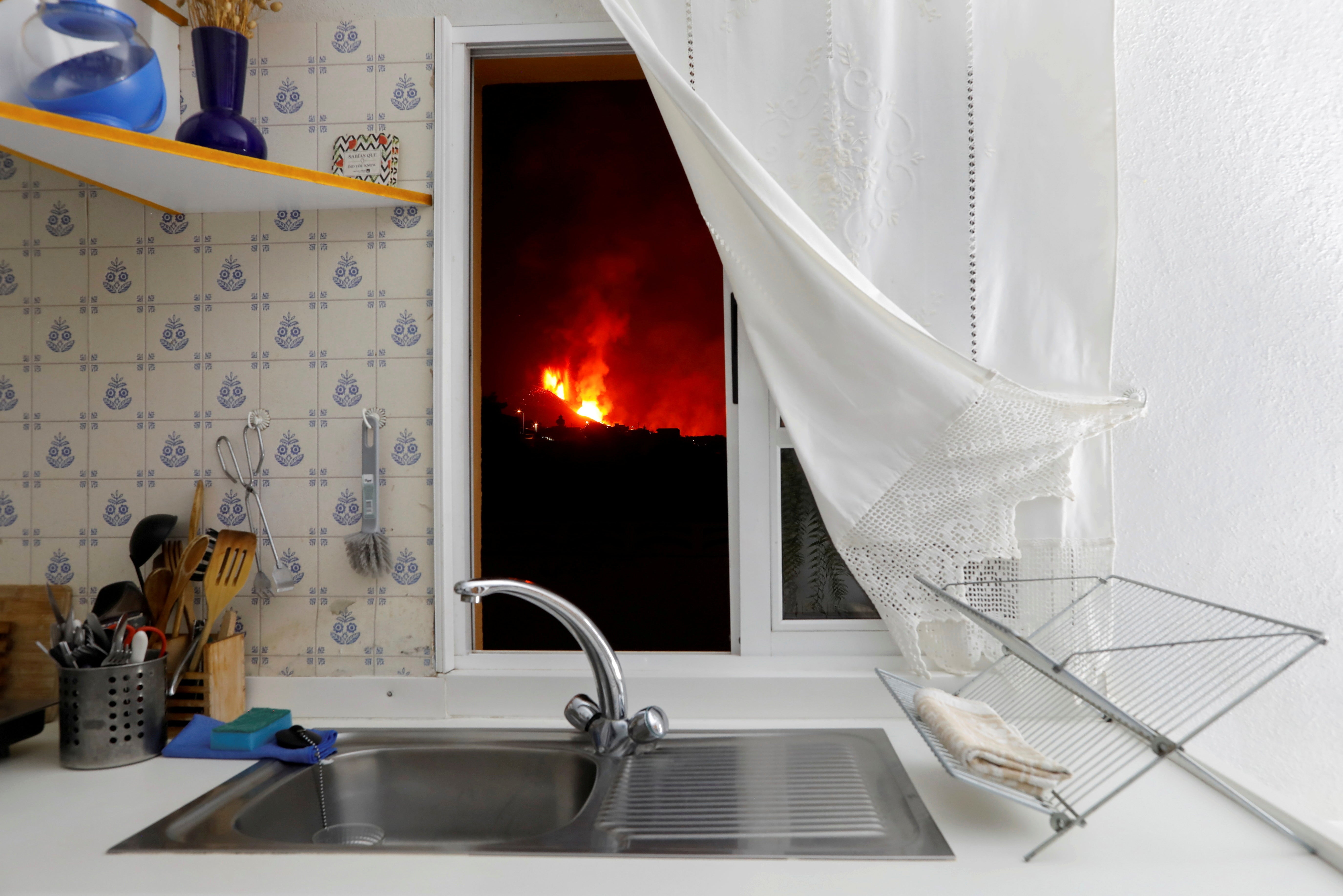 Lava is seen through the window of a kitchen following the eruption of a volcano on the Spanish island of La Palma