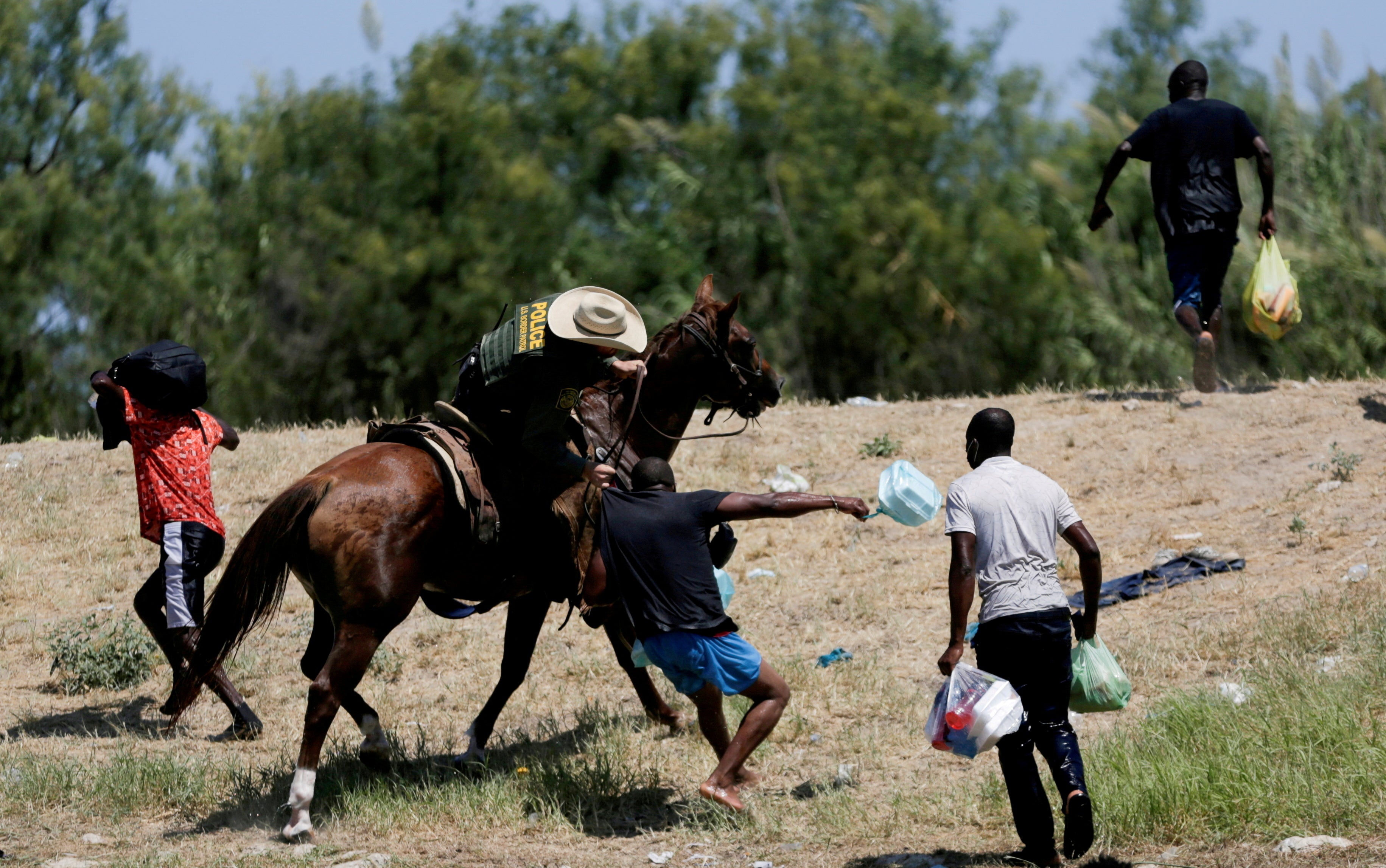 A US border patrol officer grabs the shirt of a migrant trying to return to the United States along the Rio Grande river, after having crossed into Mexico to buy food