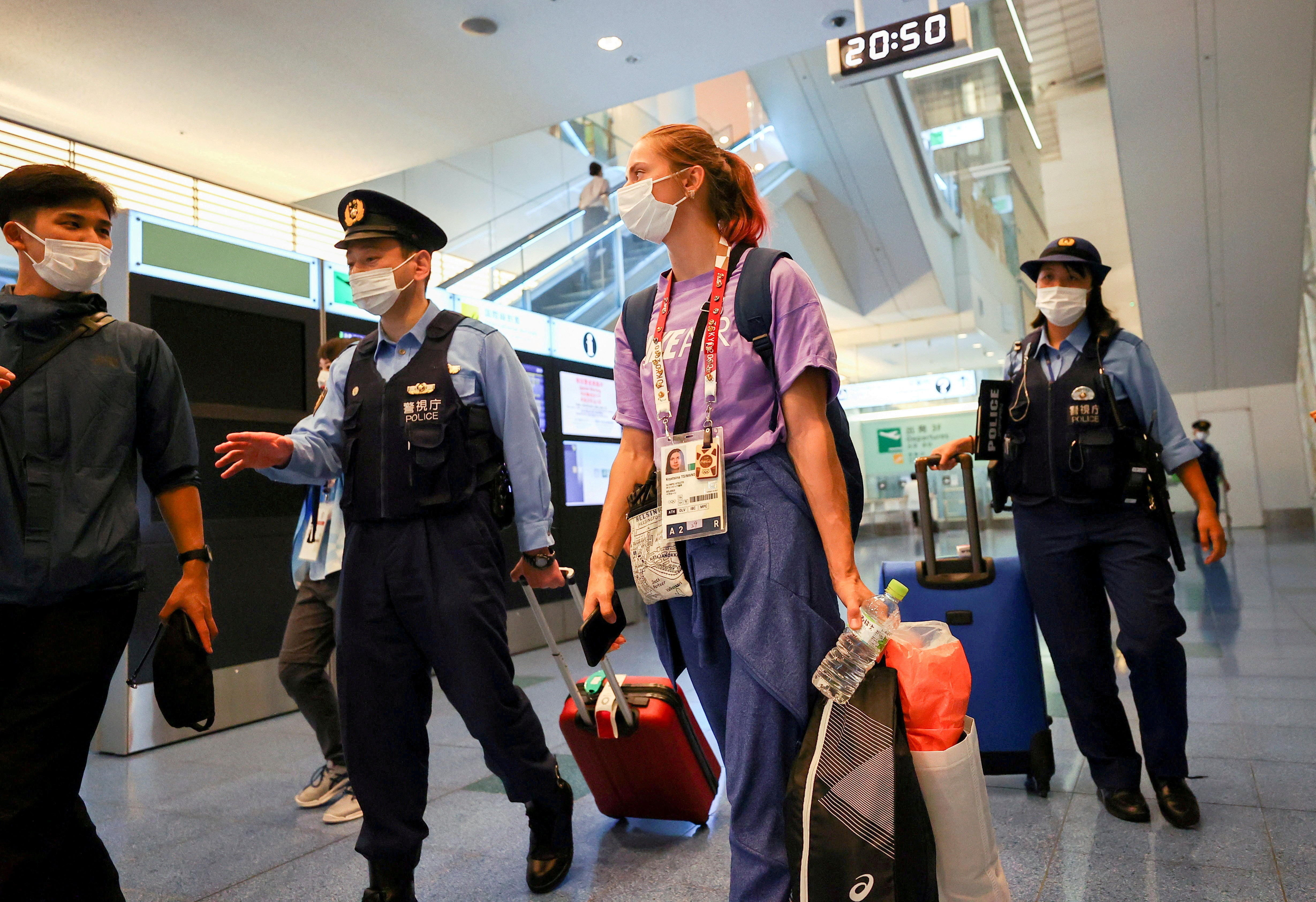 Belarusian athlete Krystsina Tsimanouskaya is escorted by Japanese police officers at Haneda international airport in Tokyo