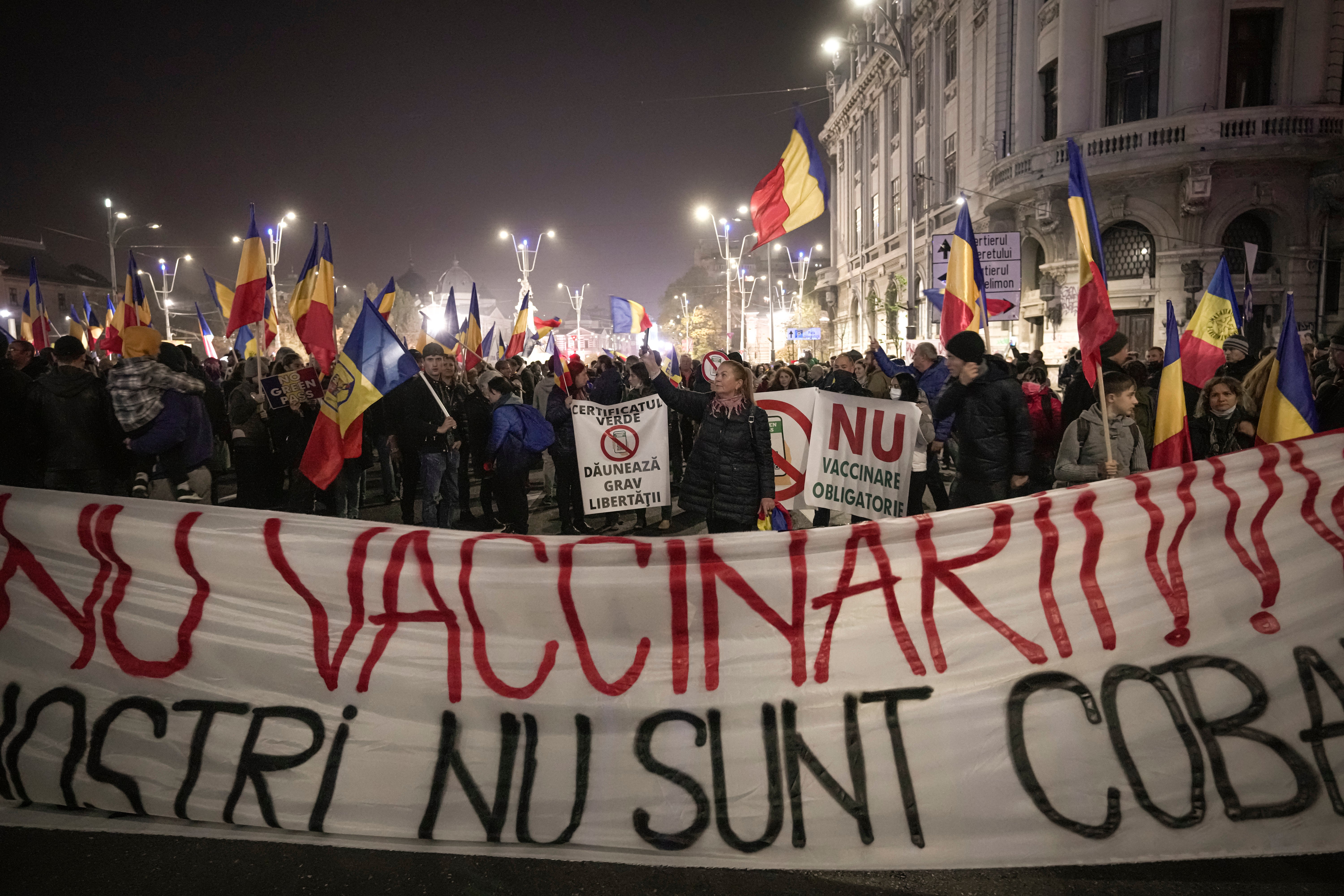 People hold a large banner that reads “No to Vaccination – Our Children are not your guinea pigs” during a protest against vaccinations in Bucharest