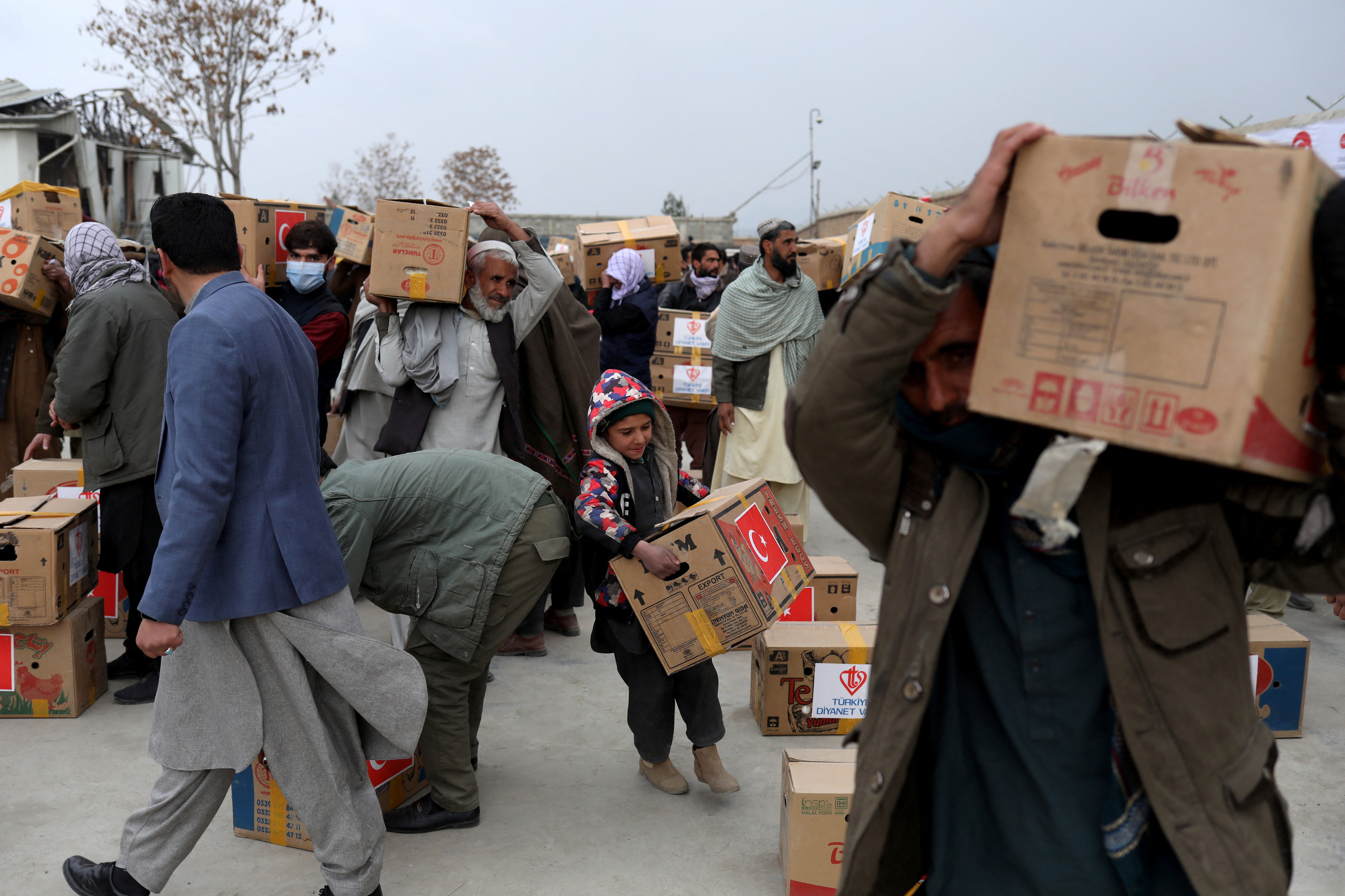 Afghans carrying packages distributed by a Turkish humanitarian aid group, leave a distribution centre in Kabul