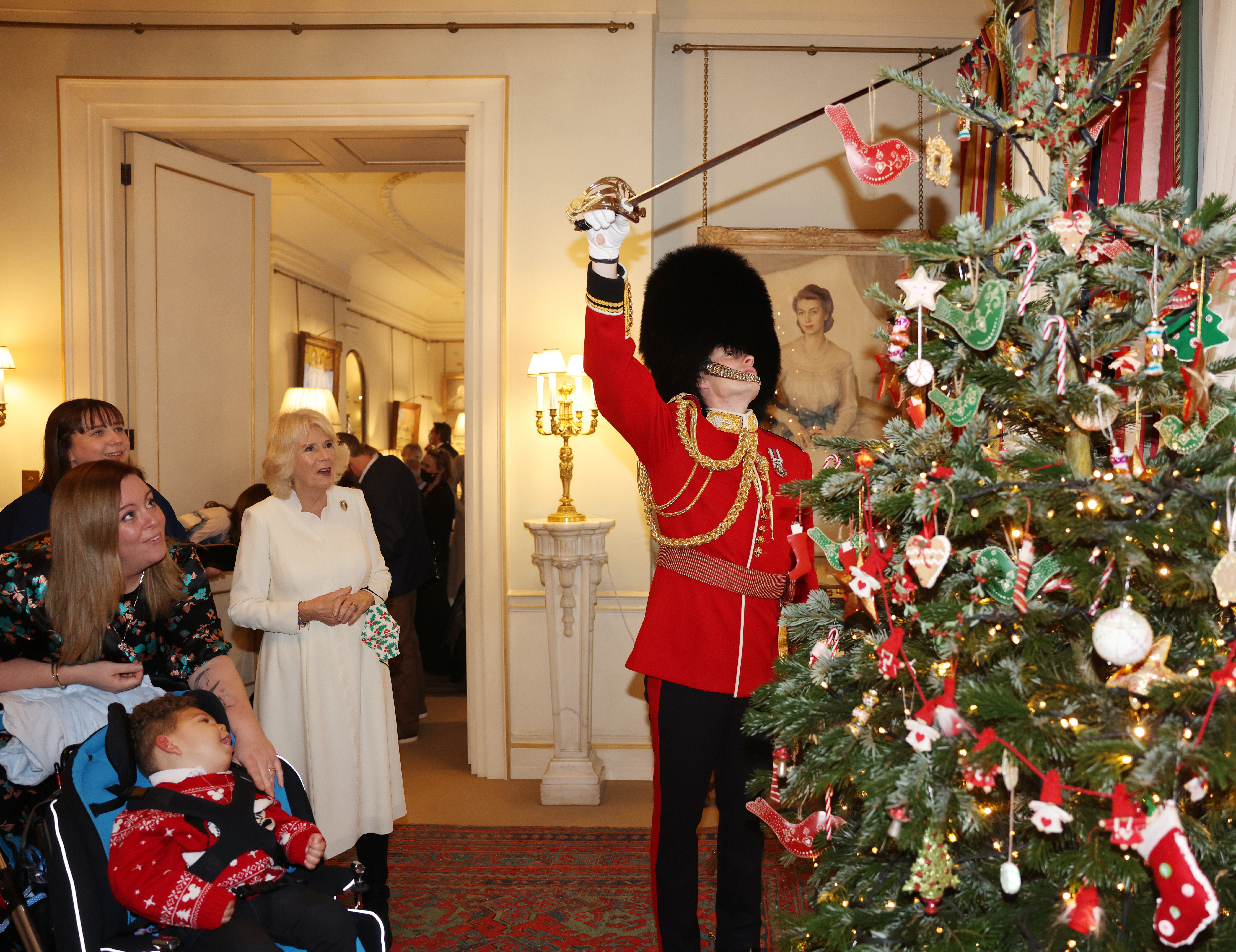 The Duchess of Cornwall watches as royal equerry Ed Andersen, of the Welsh Guards, helps children decorate the Christmas tree at Clarence House (Ian Vogler/Daily Mirror/PA)