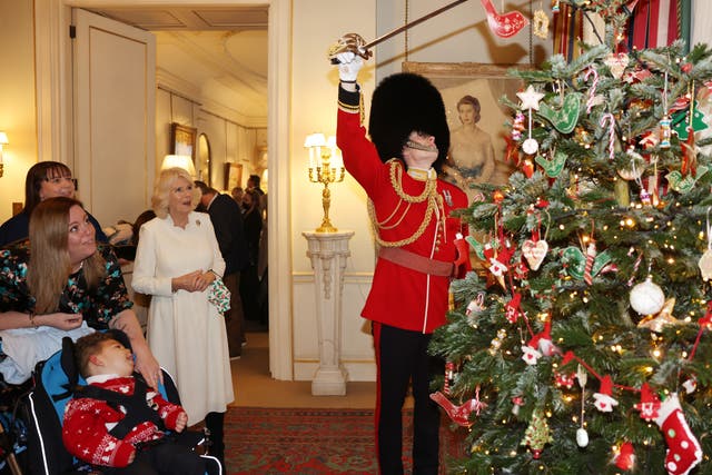 The Duchess of Cornwall watches as royal equerry Ed Andersen, of the Welsh Guards, helps children decorate the Christmas tree at Clarence House (Ian Vogler/Daily Mirror/PA)