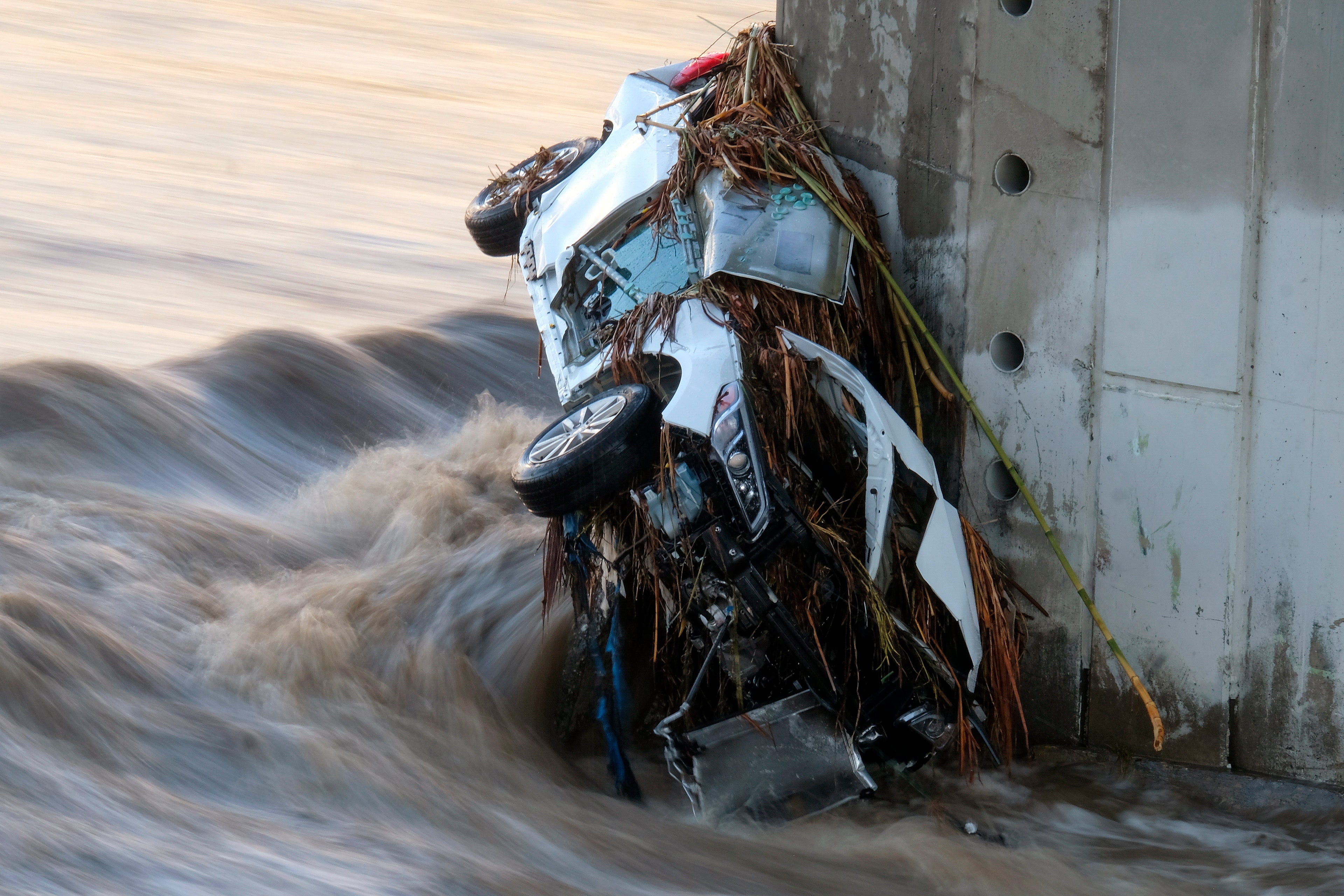 A vehicle is seen in the Los Angeles River at the Washington Bridge near downtown Los Angeles on Tuesday, Dec. 14, 2021. Rain is drenching Southern California as a blustery storm charged down the state