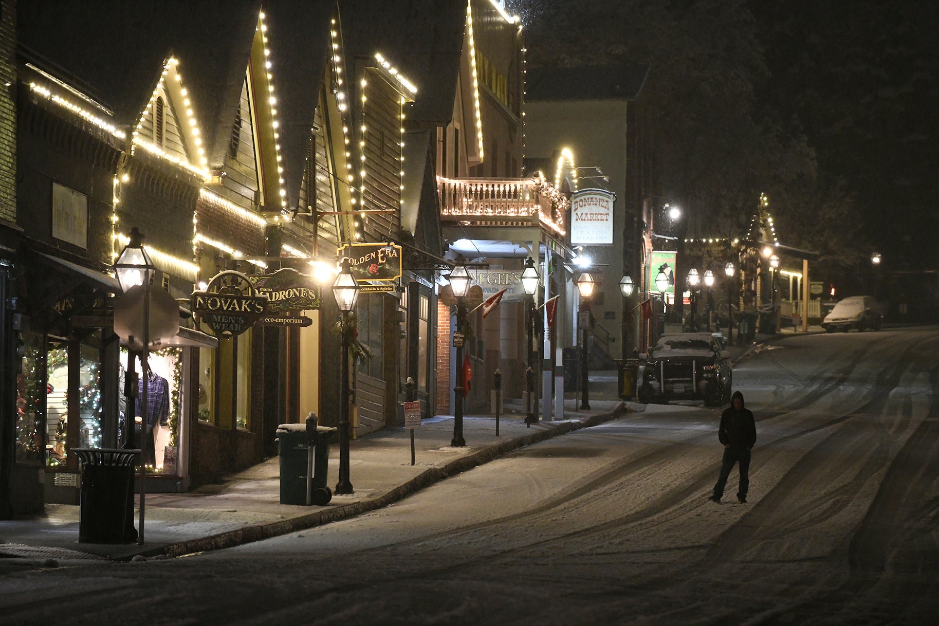 A pedestrian walks along a silent and snowy Broad Street, early Tuesday, Dec. 14, 2021, in Nevada City, California